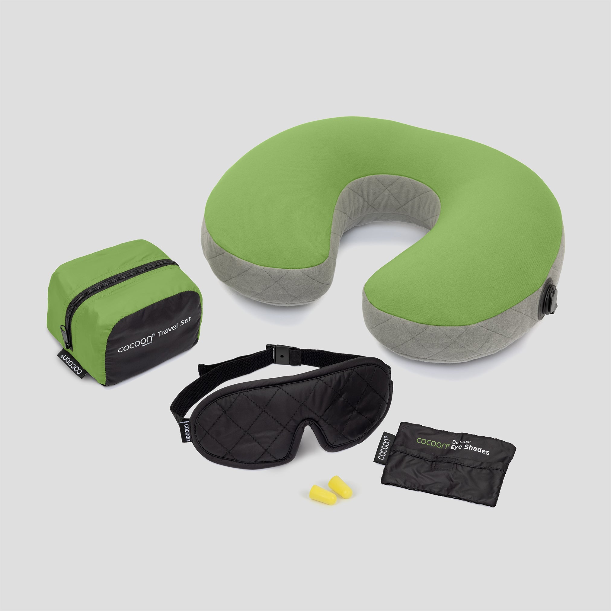 Green travel pillow with matching eye mask, earplugs, and pouch on a light gray background