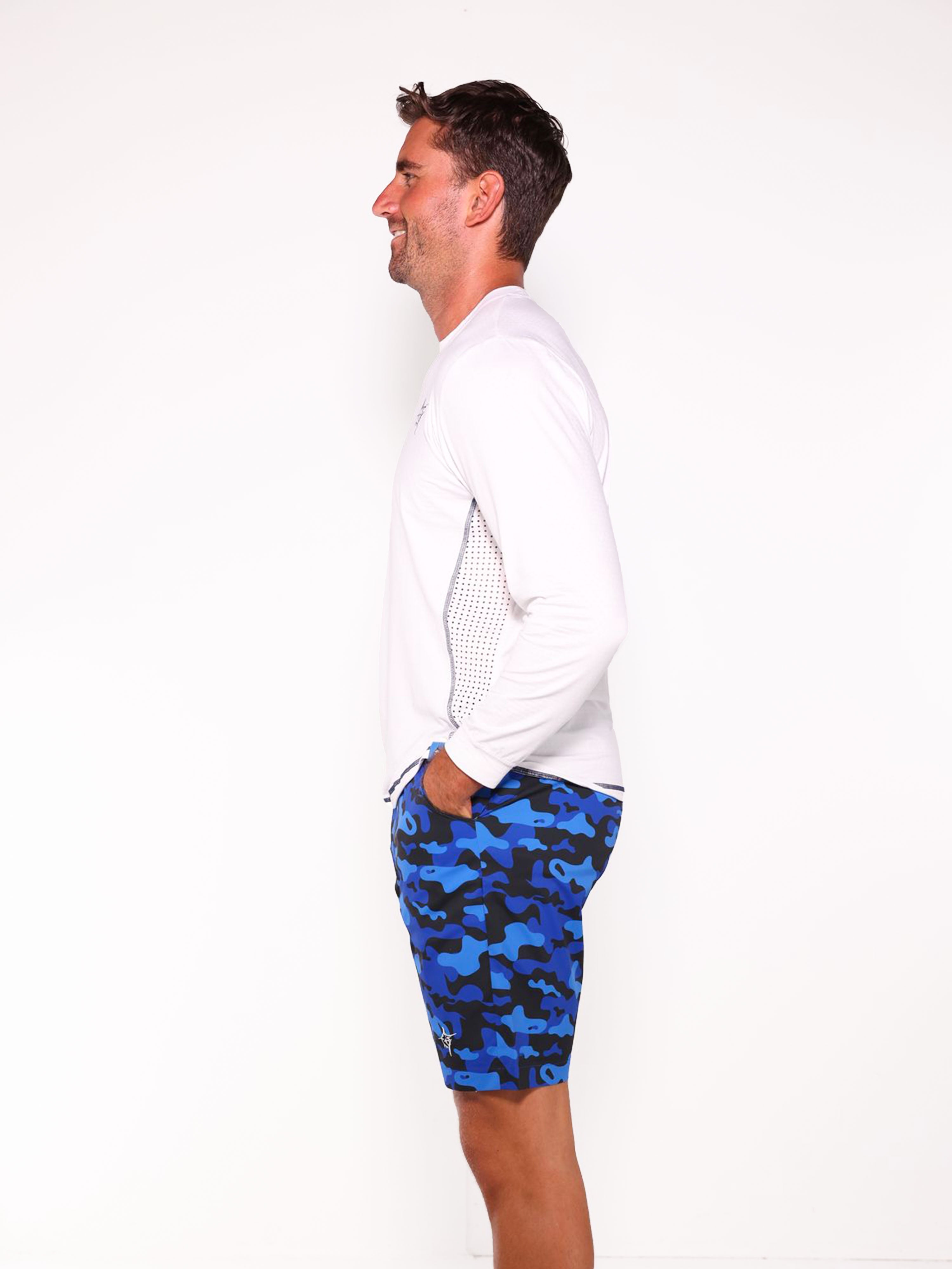 Man wearing a white long-sleeve shirt and blue camouflage shorts on a white background