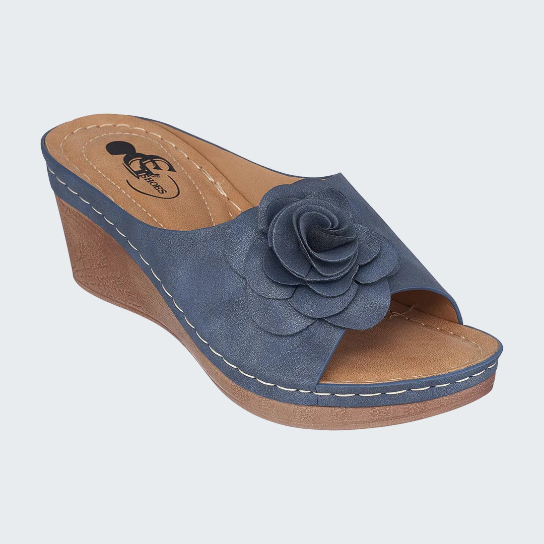 Blue wedge sandal with a flower detail on a white background