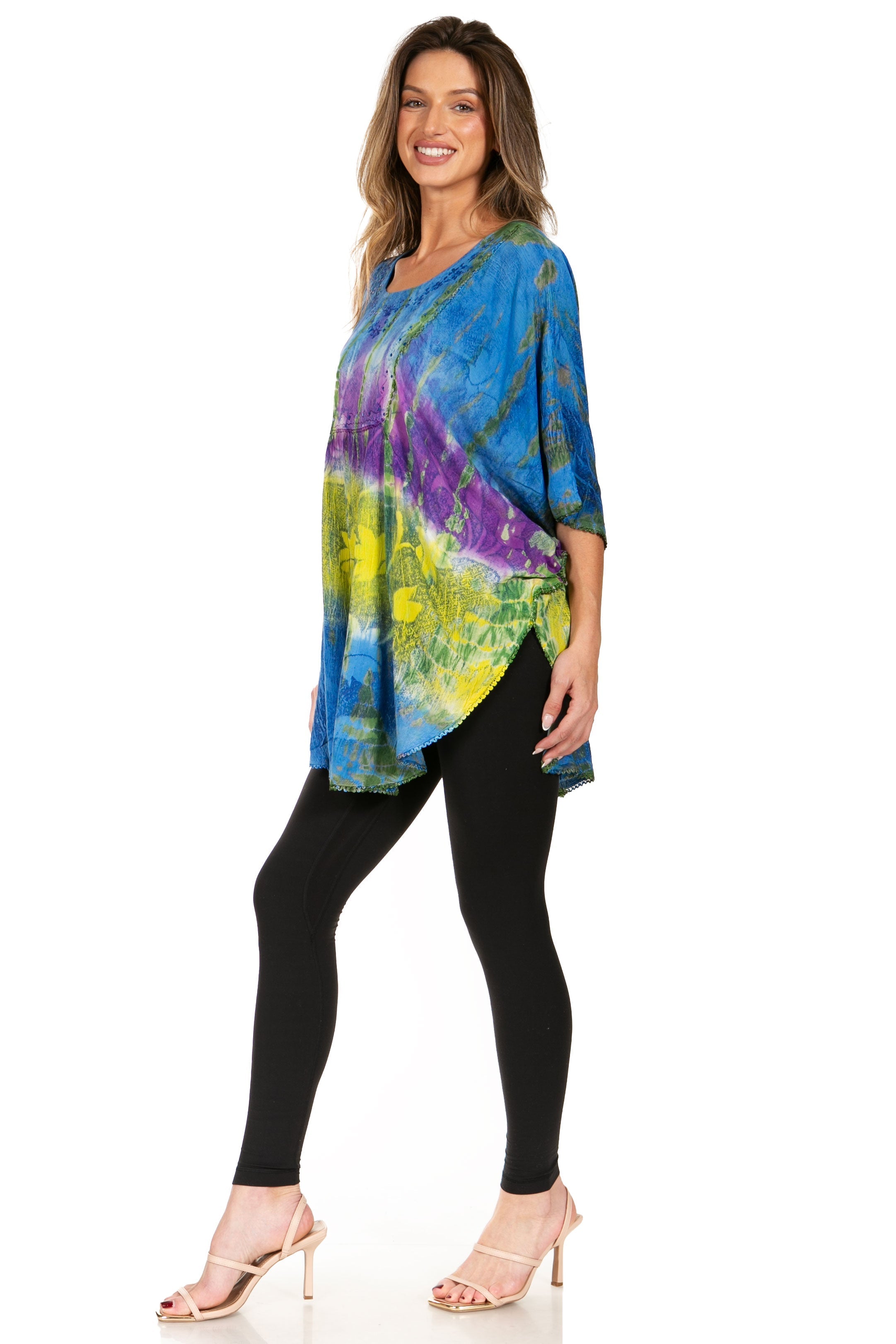 Woman wearing a colorful tie-dye top and black leggings on a white background