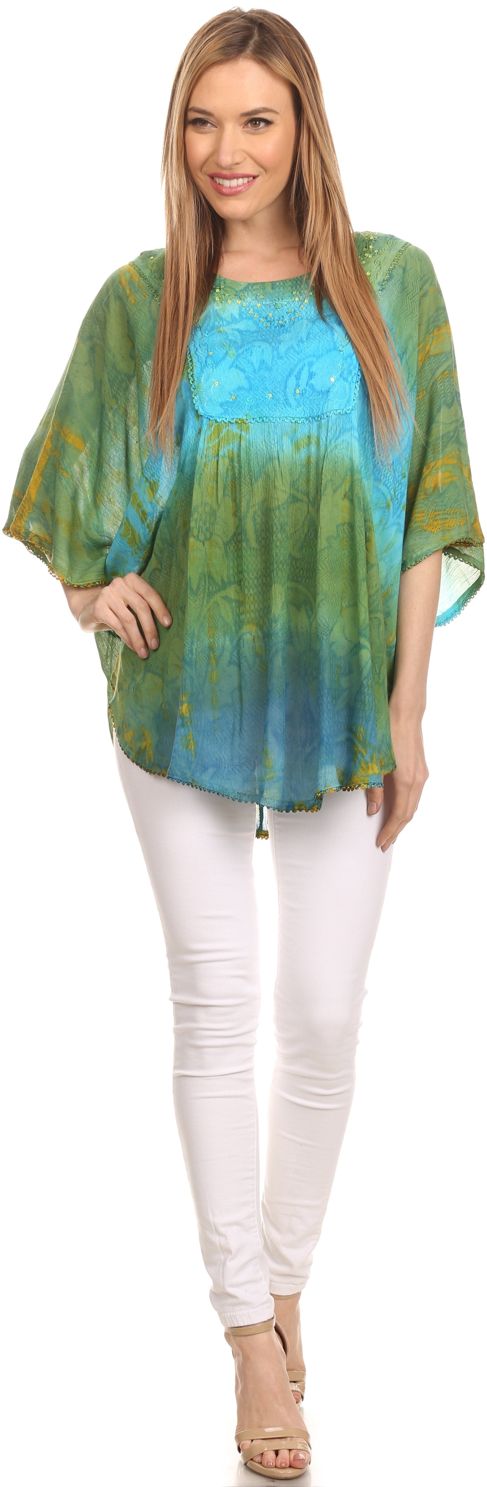 Woman wearing a tie-dye shirt and white pants on a plain background