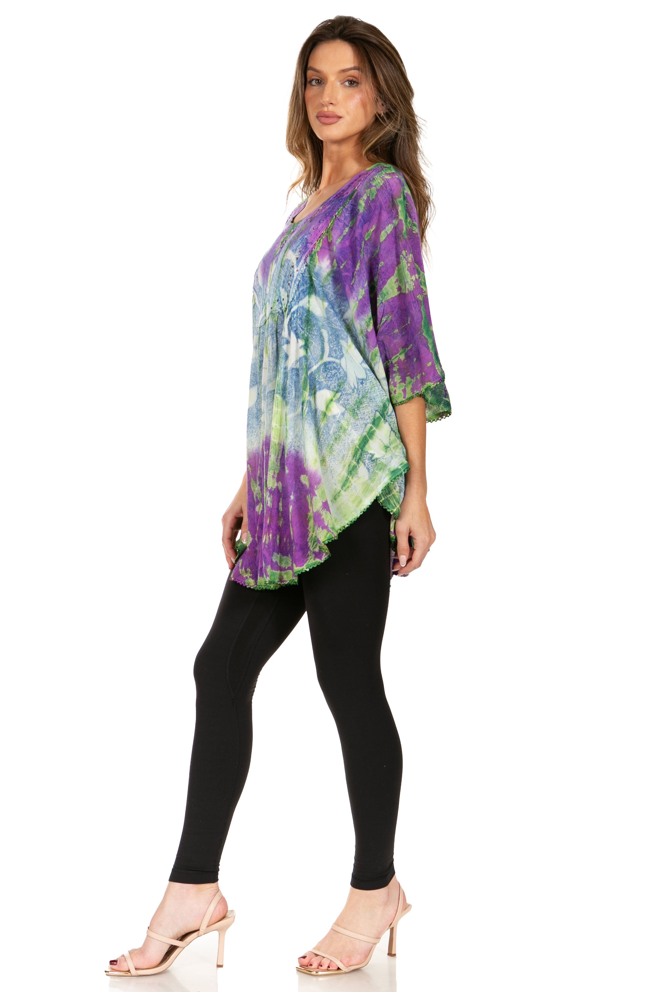 Woman wearing a colorful tie-dye top and black leggings on a white background