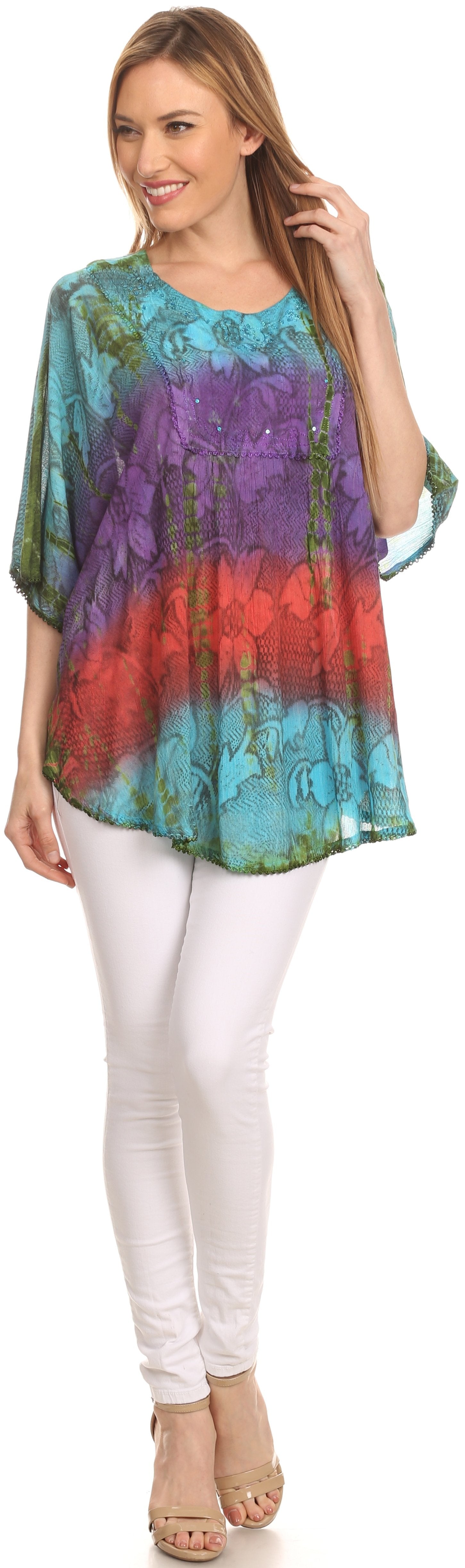 Woman wearing a colorful tie-dye shirt and white pants on a plain background