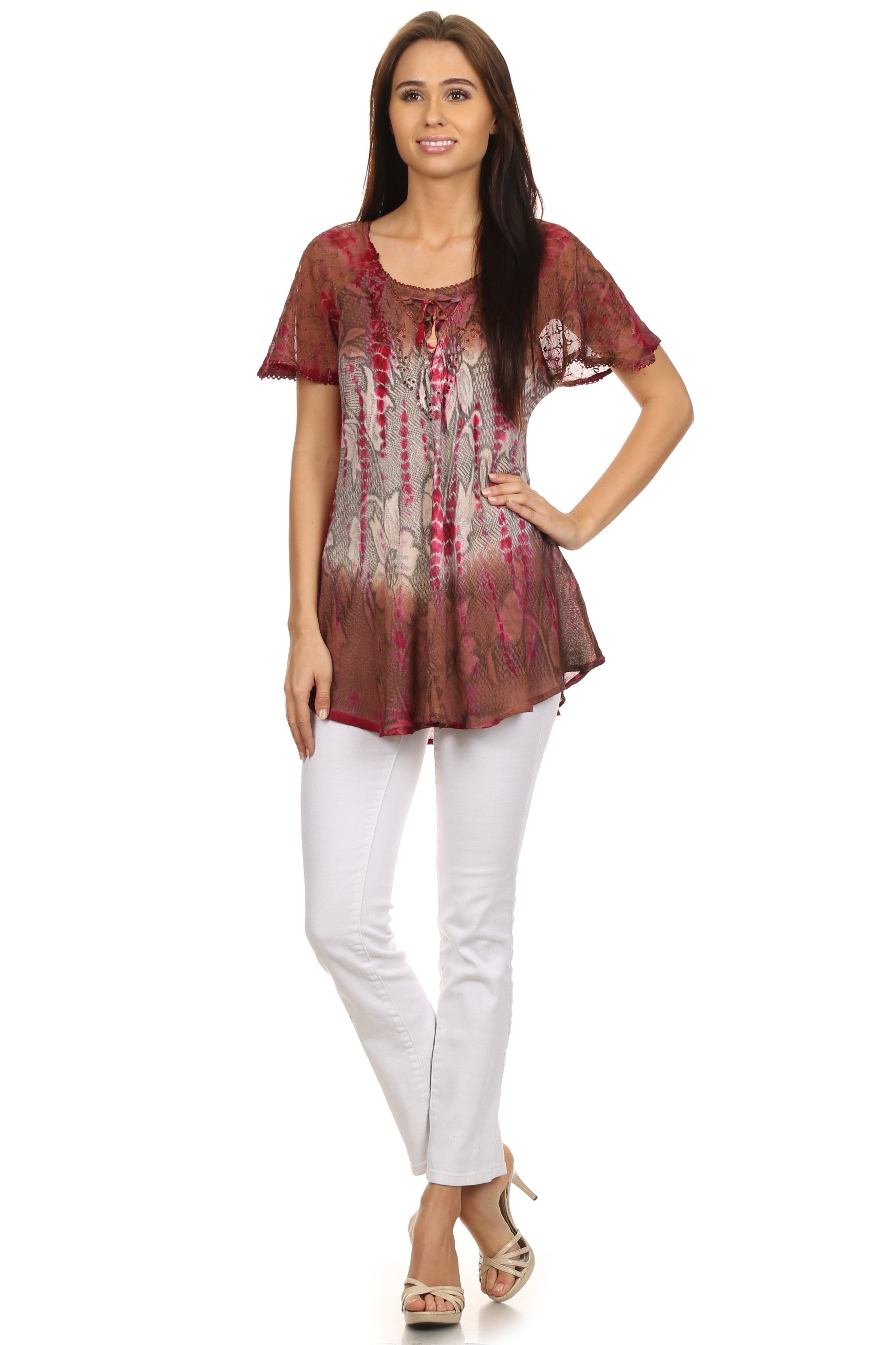 Woman wearing a patterned top and white pants on a white background