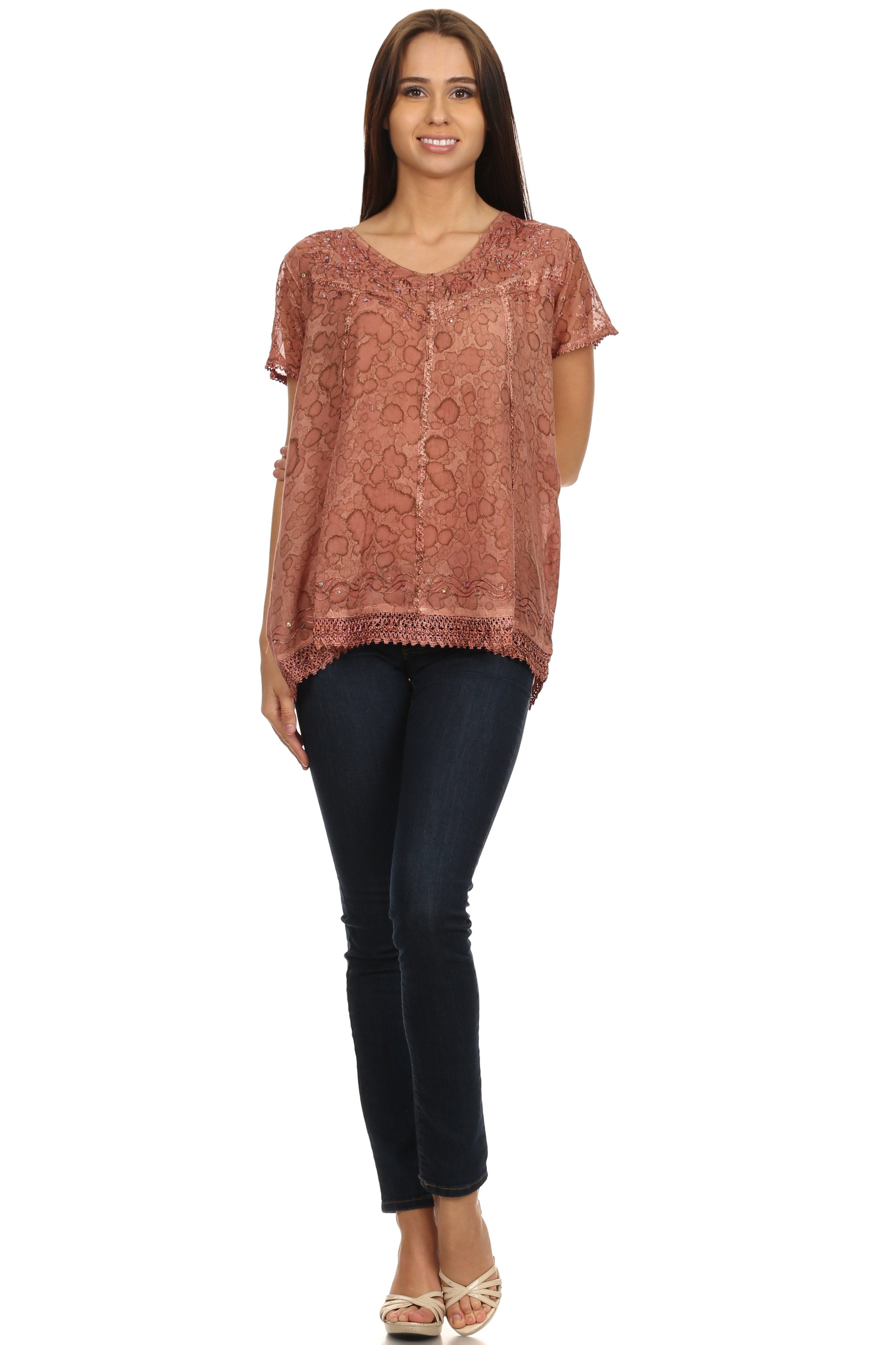 Woman wearing a patterned top and black pants on a white background