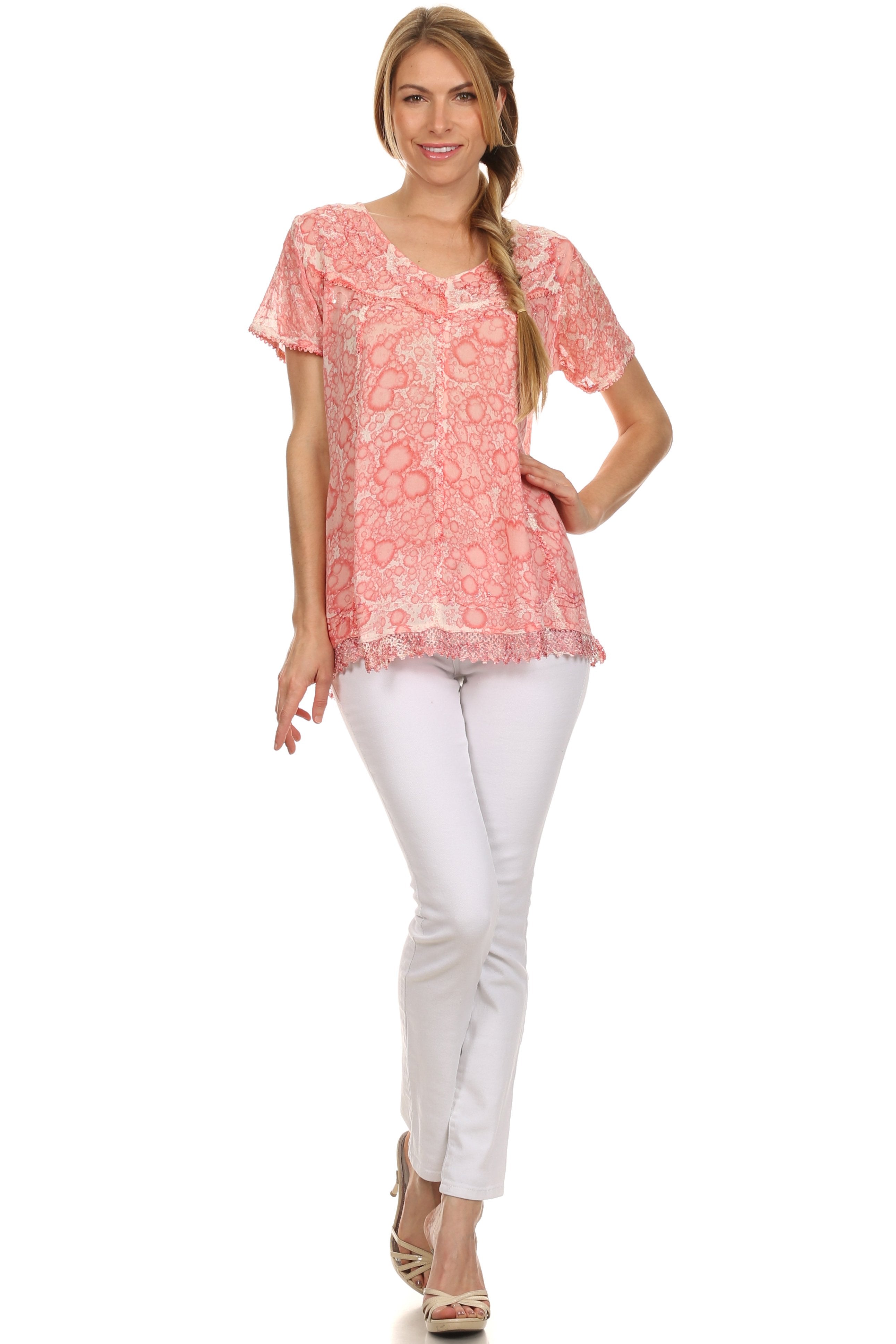 Woman wearing a coral patterned top and white pants on a white background
