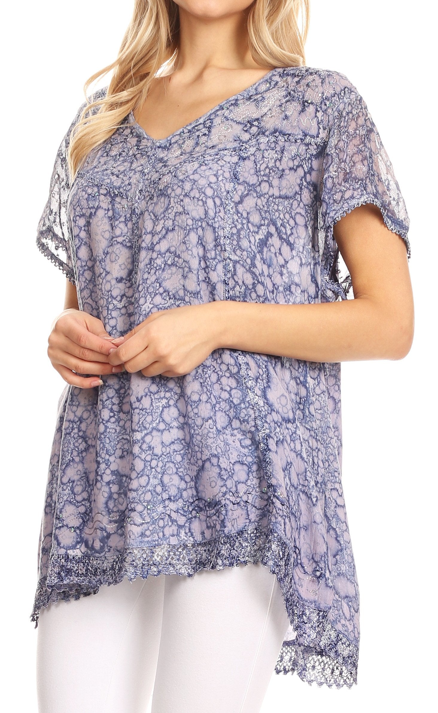 Woman wearing a blue floral patterned top with white pants on a white background