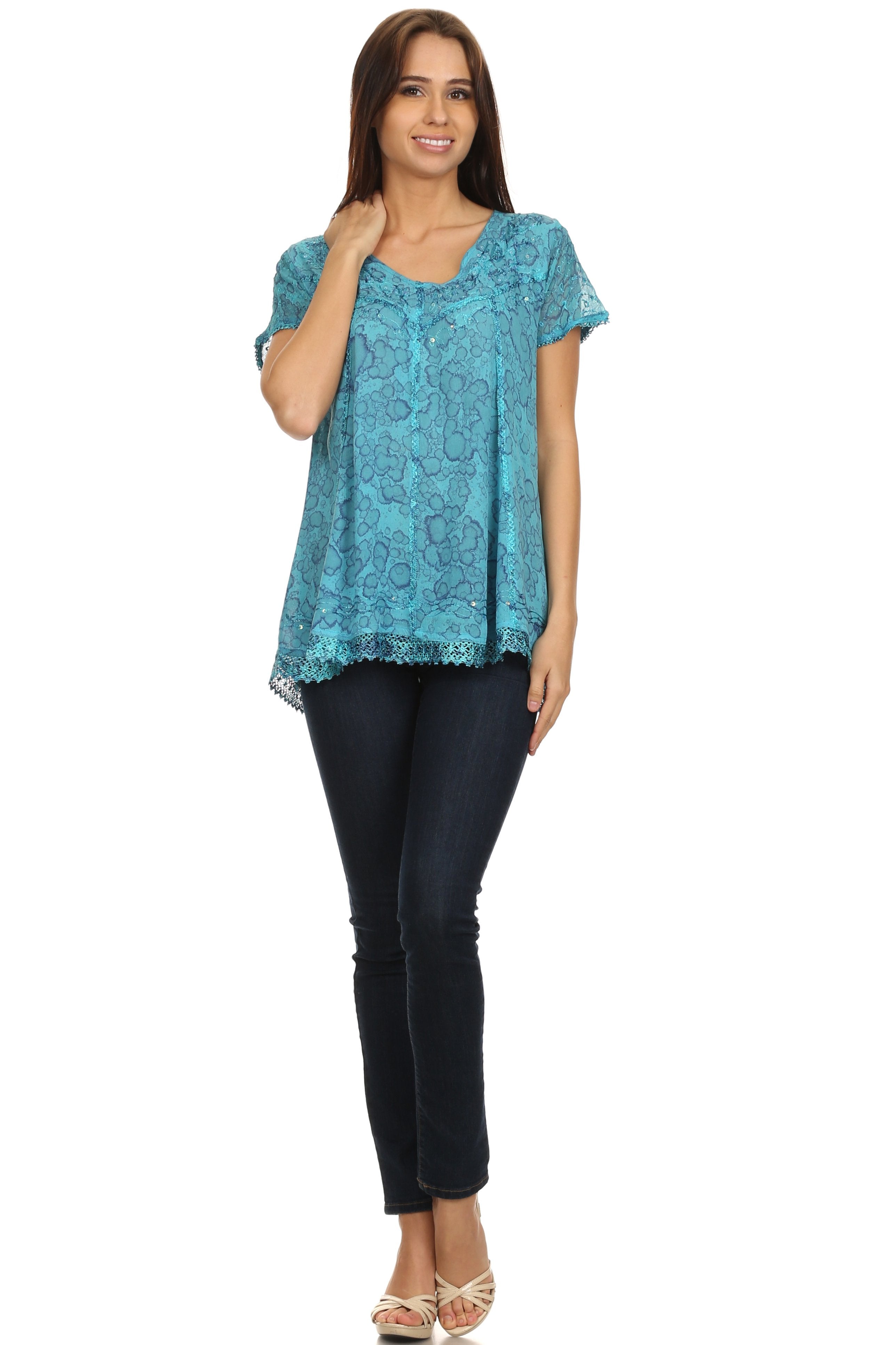 Woman wearing a blue lace top and black pants on a white background