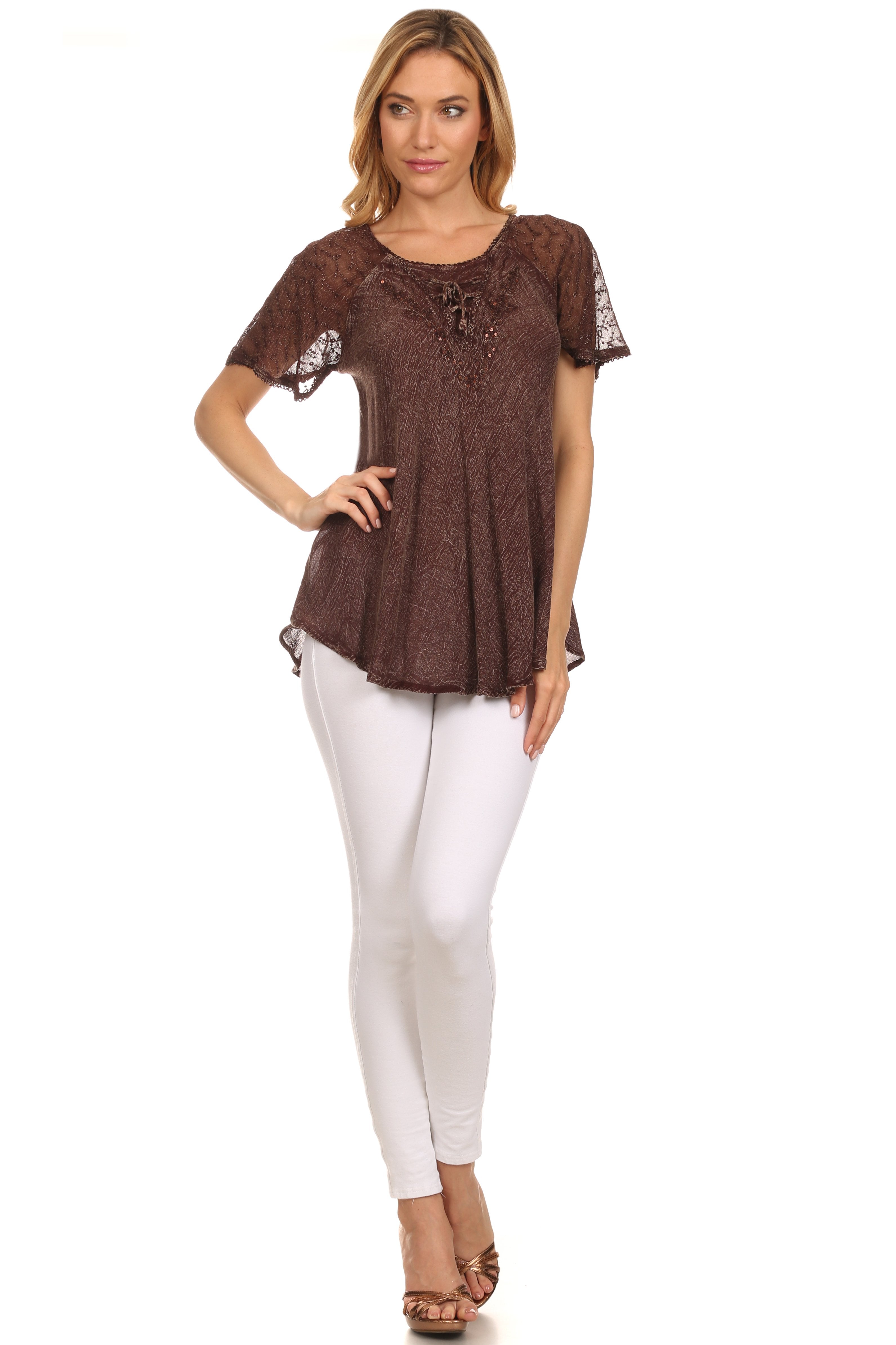 Woman wearing a brown patterned top and white pants on a white background