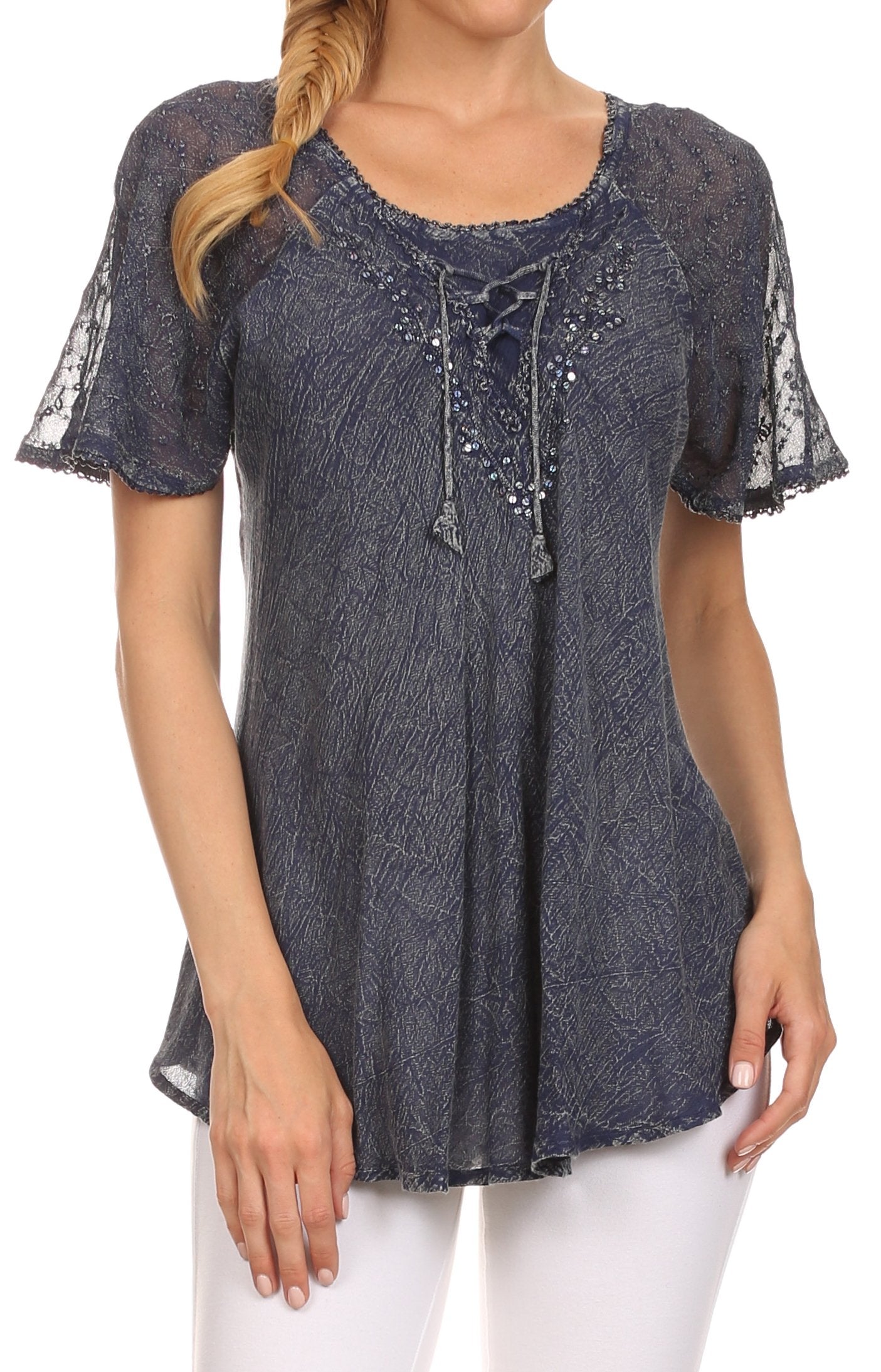 Woman wearing a dark blue embroidered top with sheer sleeves on a white background