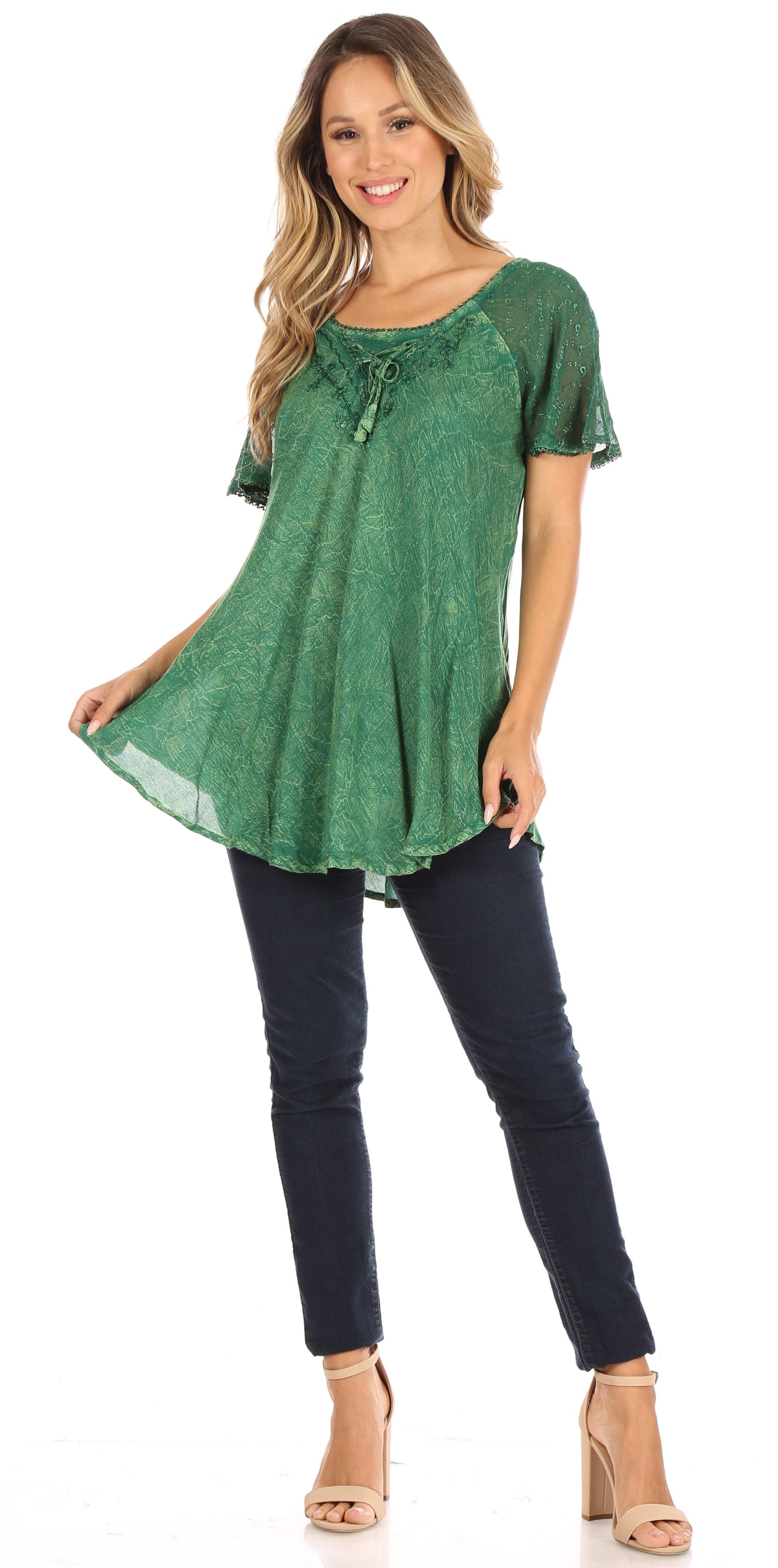 Woman wearing a green patterned top and black pants on a white background
