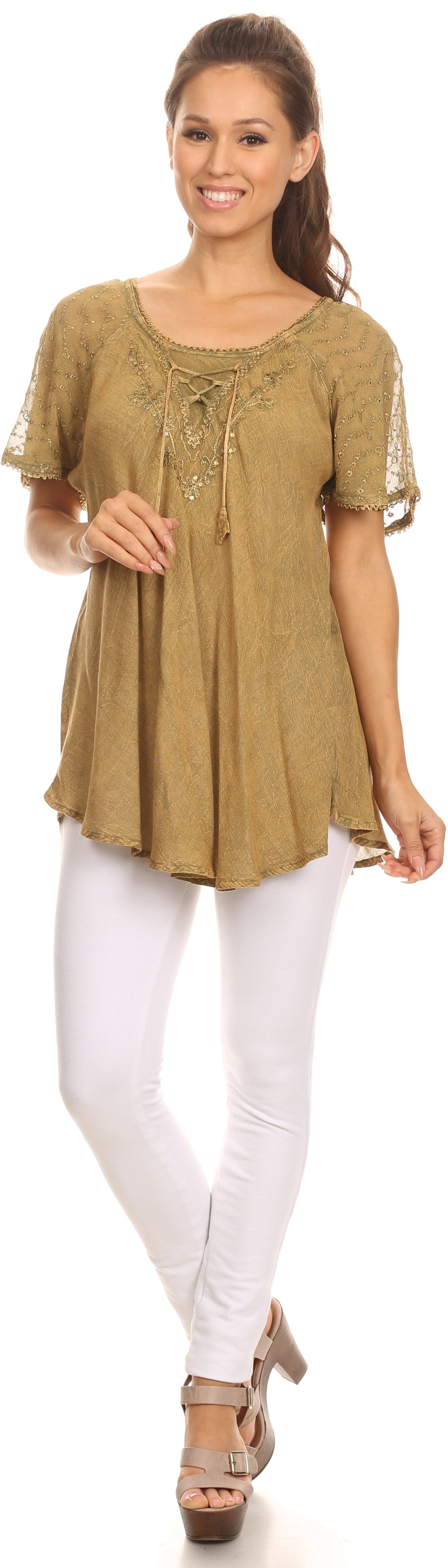 Woman wearing a beige lace-up top and white pants on a plain background