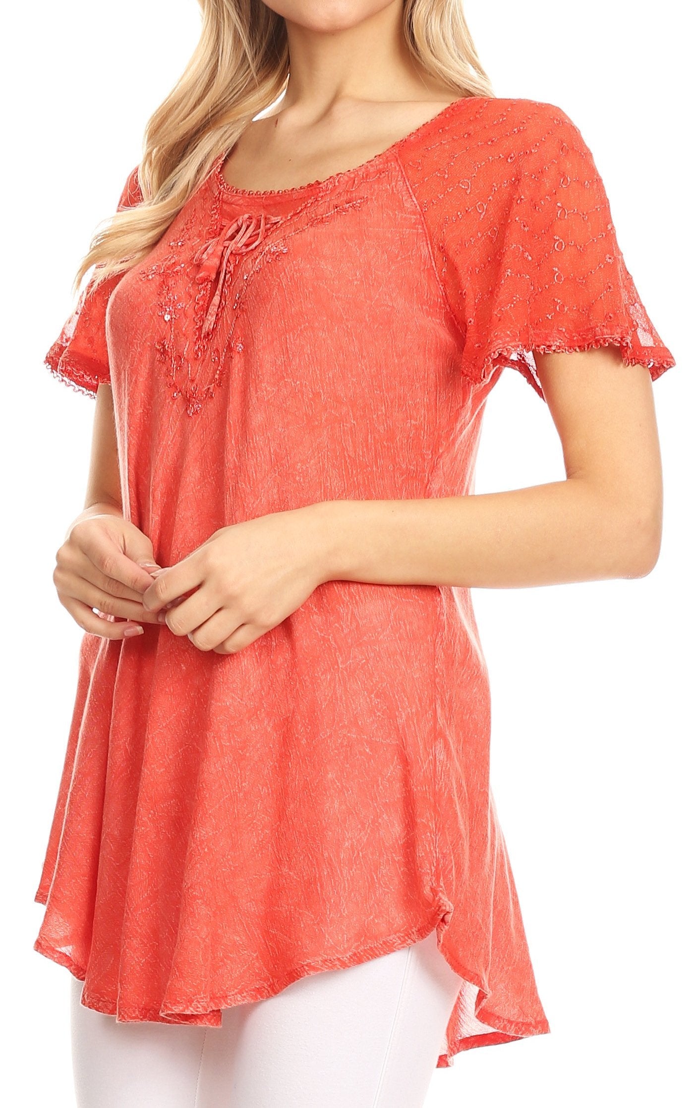 Woman wearing a coral pink blouse with lace details on a white background
