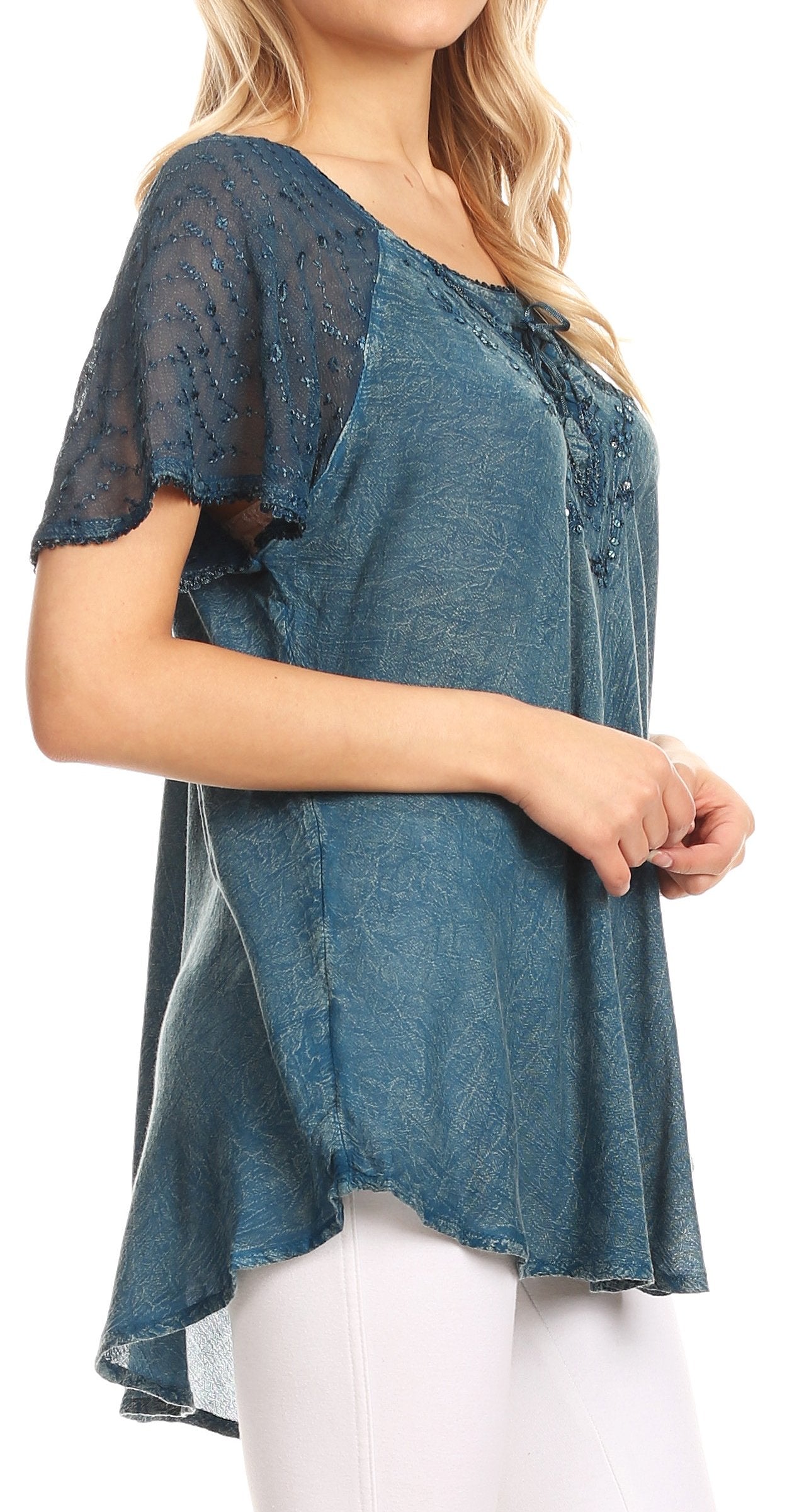 Woman wearing a blue lace top with white pants on a white background