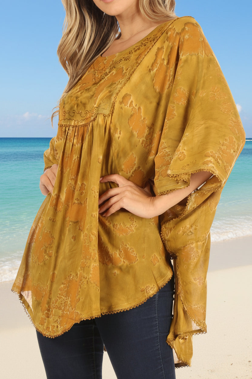 Woman wearing a mustard yellow patterned blouse with blue jeans on a white background