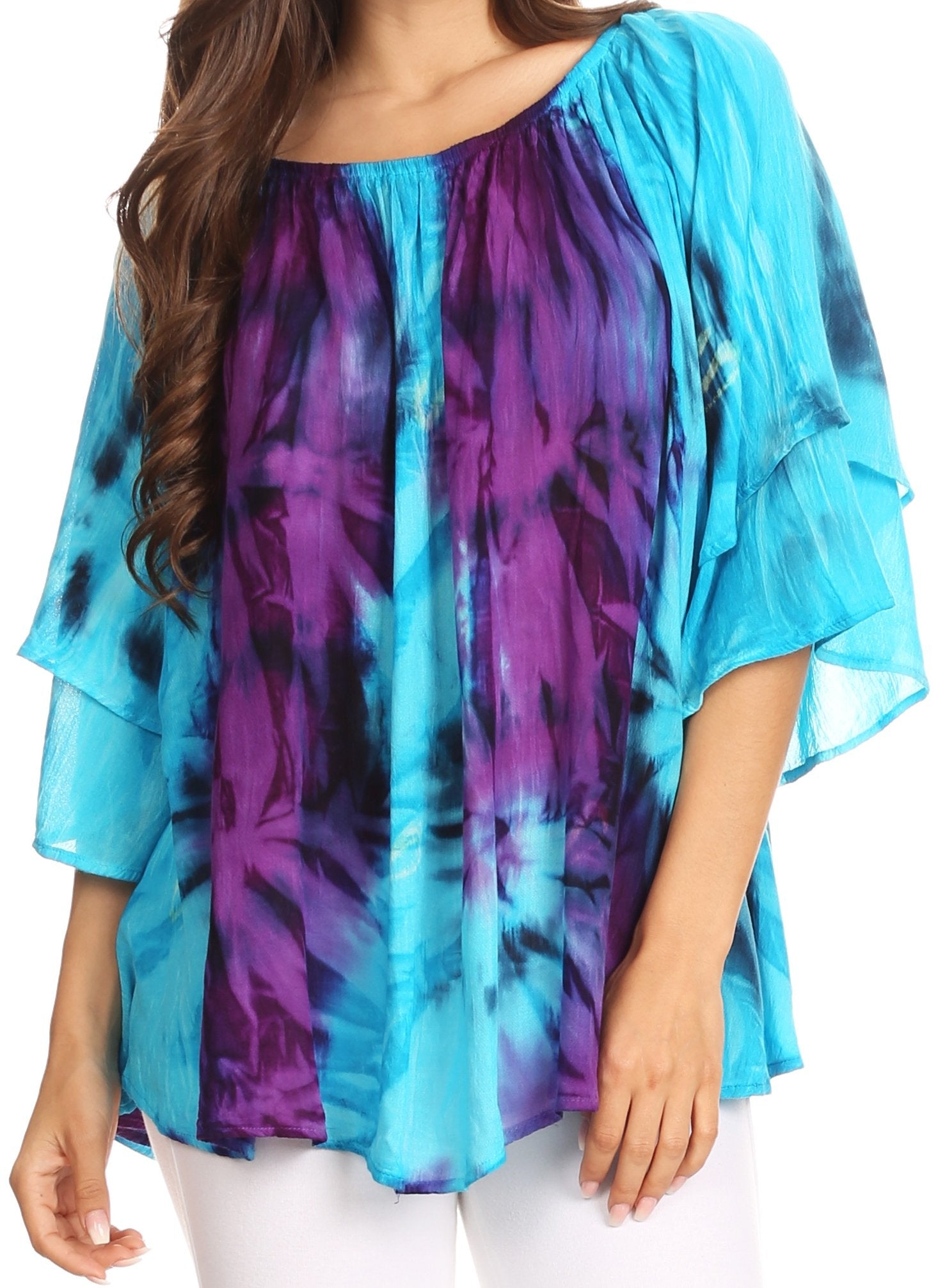 Woman wearing a blue and purple tie-dye top with white pants on a white background