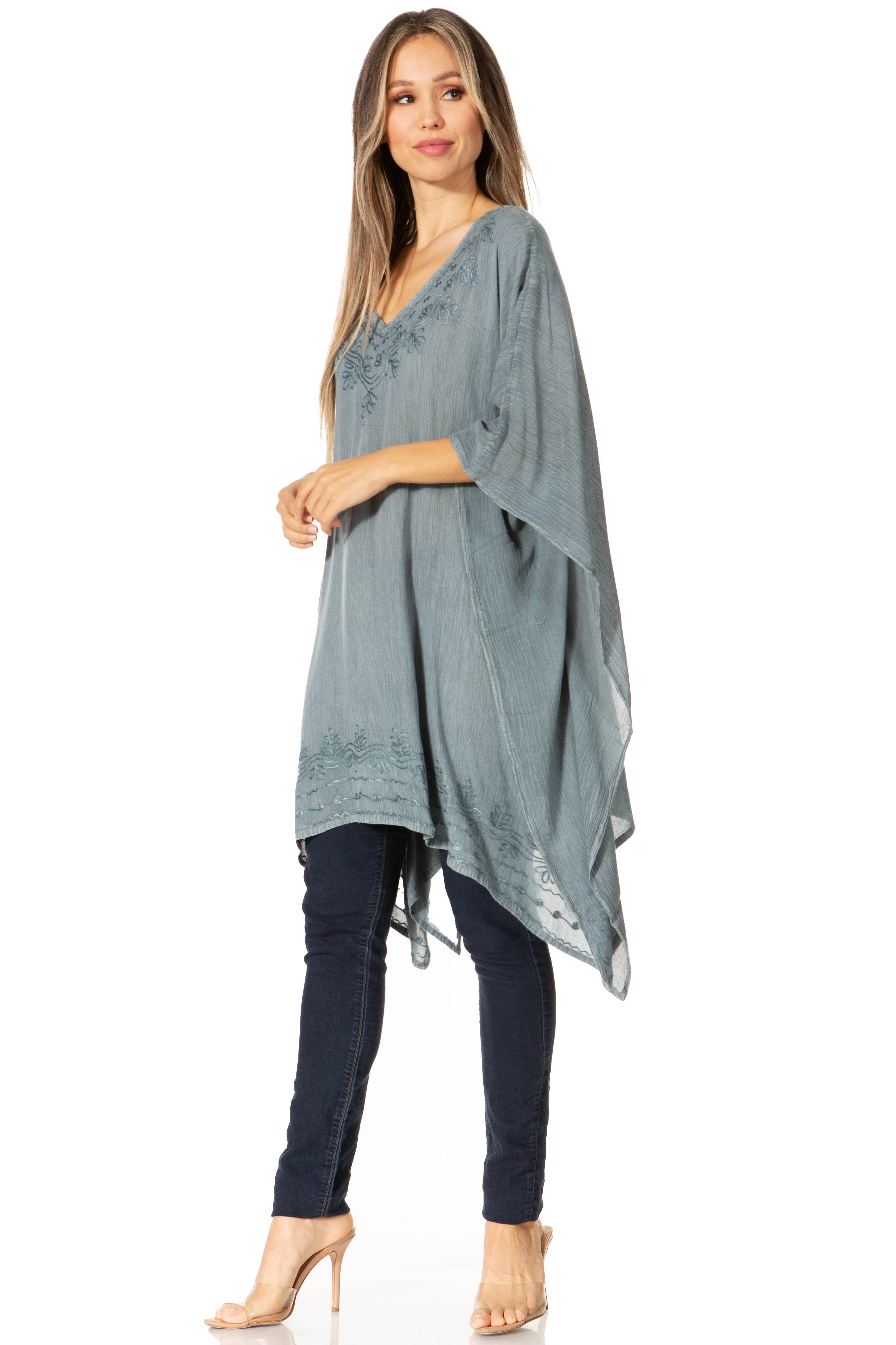 Woman wearing a gray poncho over a dark outfit on a white background