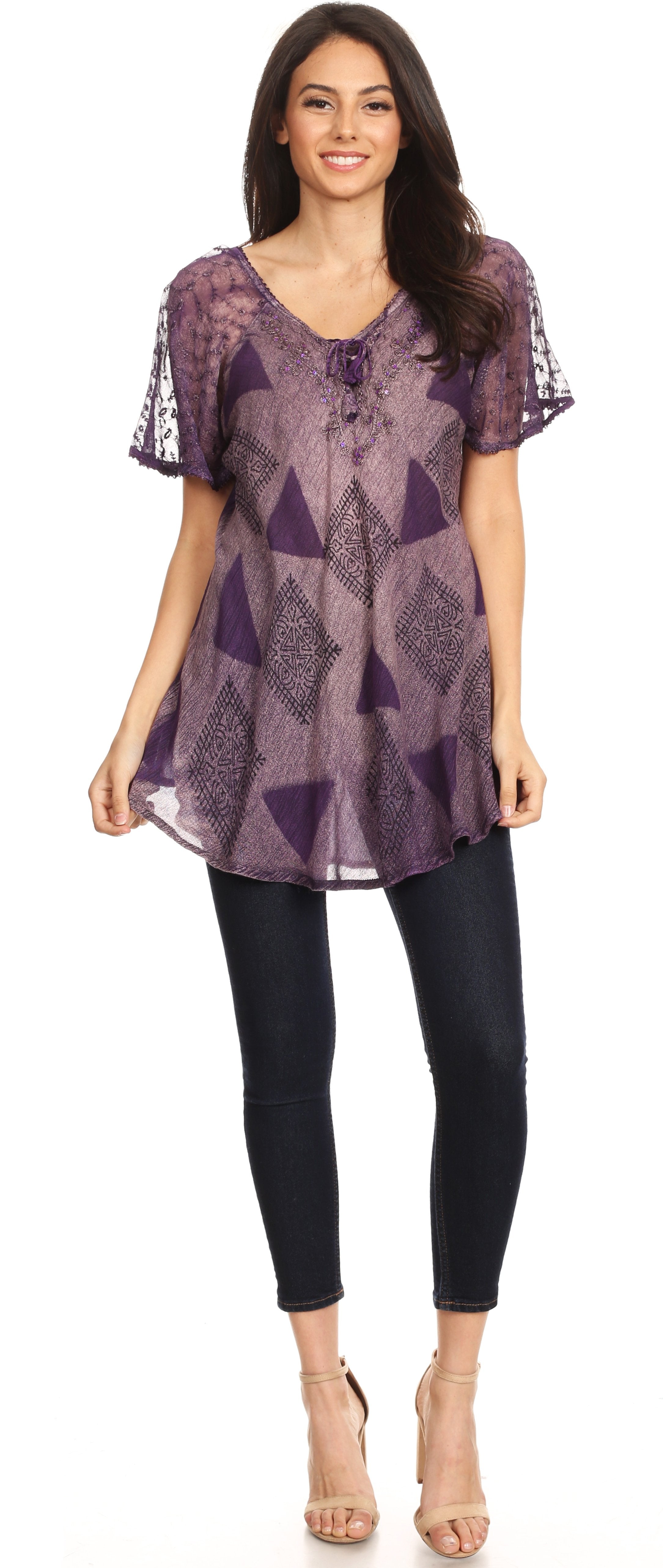 Woman wearing a purple patterned top and black pants on a white background