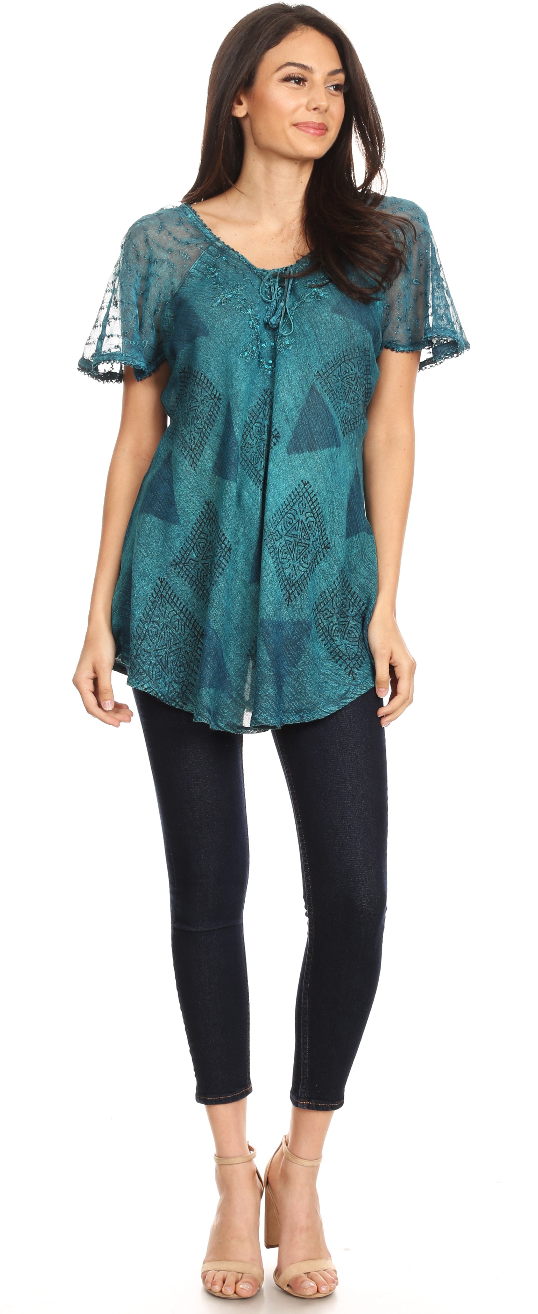 Woman wearing a teal patterned top and black pants on a white background