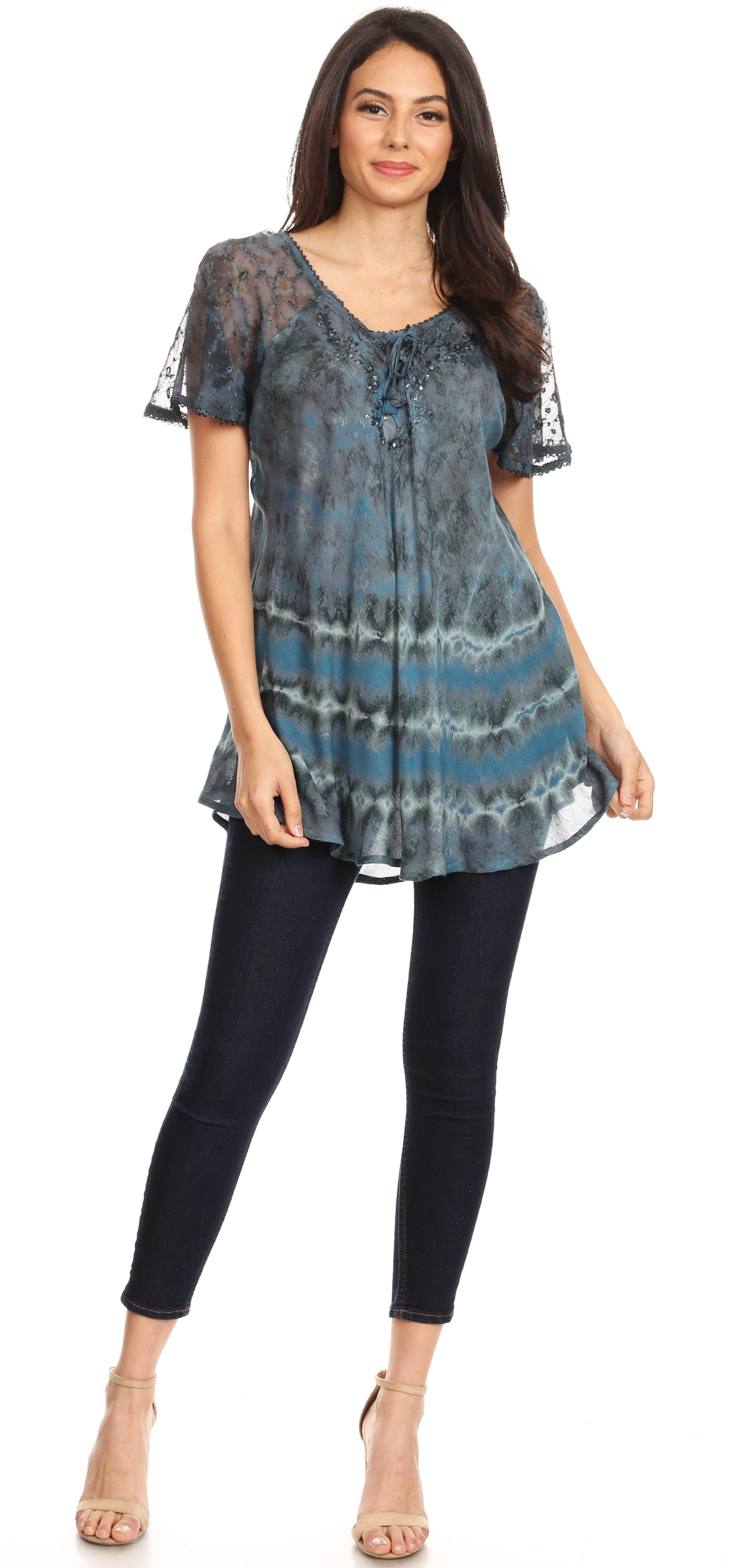Woman wearing a patterned blue and black top with black leggings on a white background