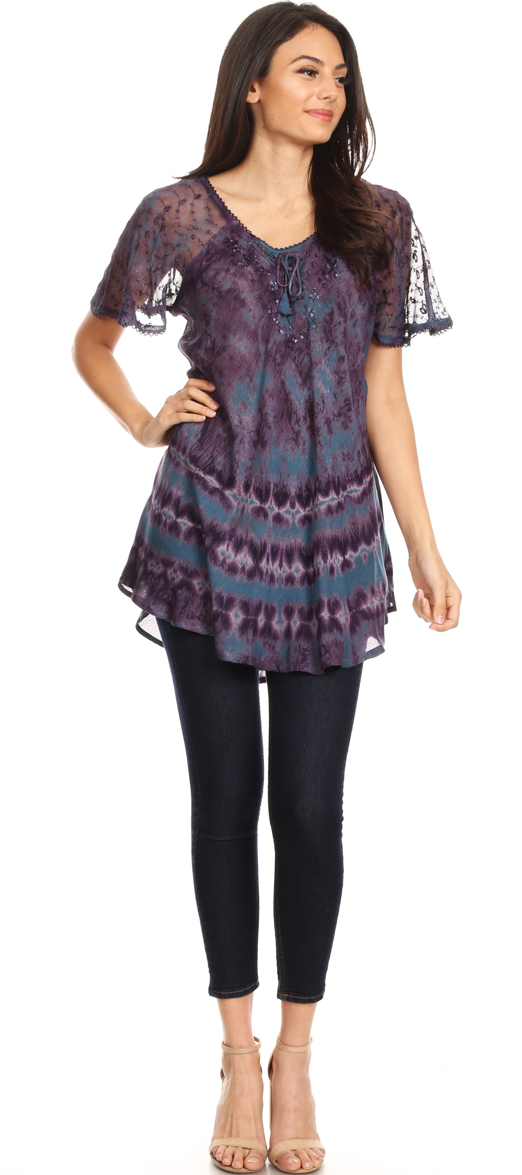 Woman wearing a patterned tunic and black pants on a white background