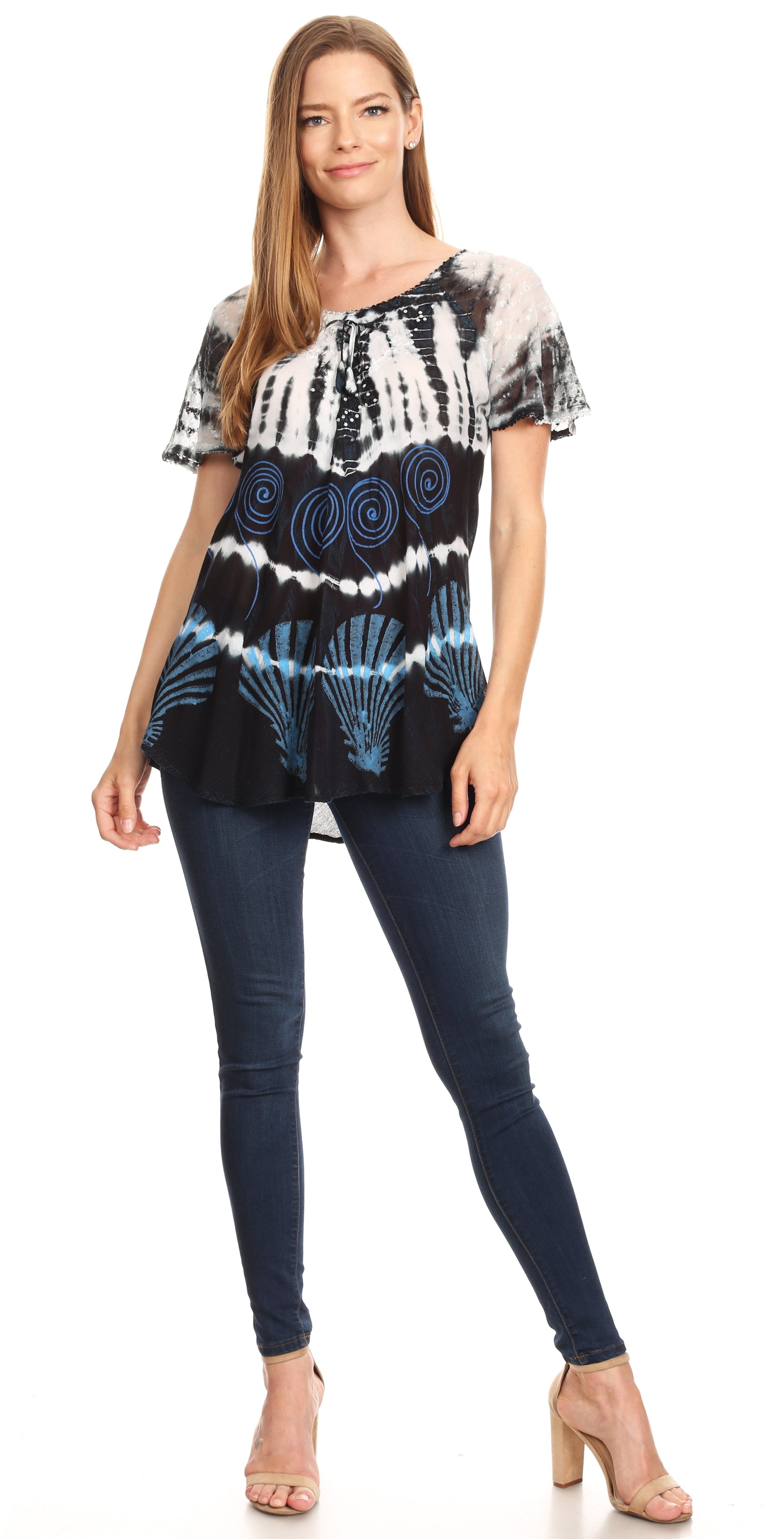 Woman wearing a patterned top and dark jeans on a white background