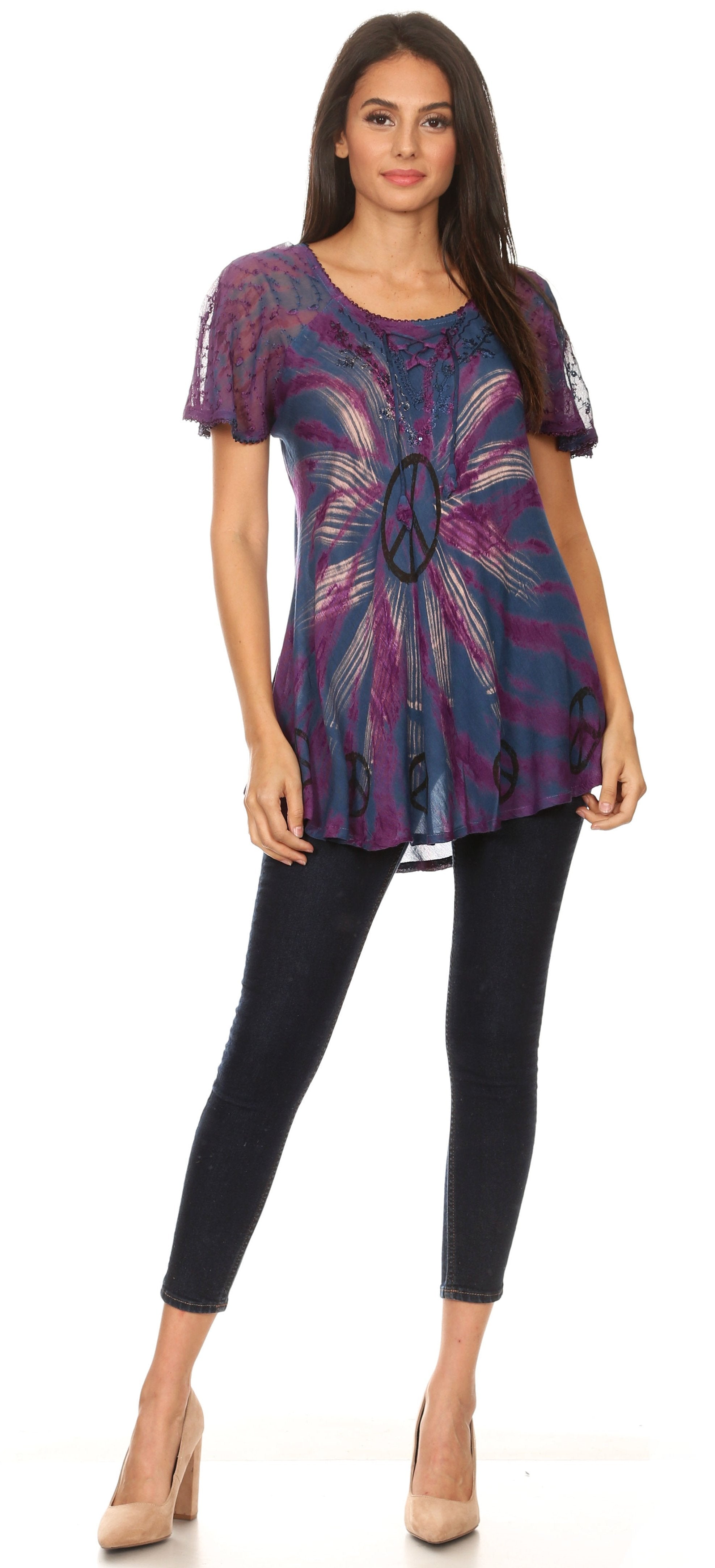 Woman wearing a patterned top with a peace symbol and black pants on a white background