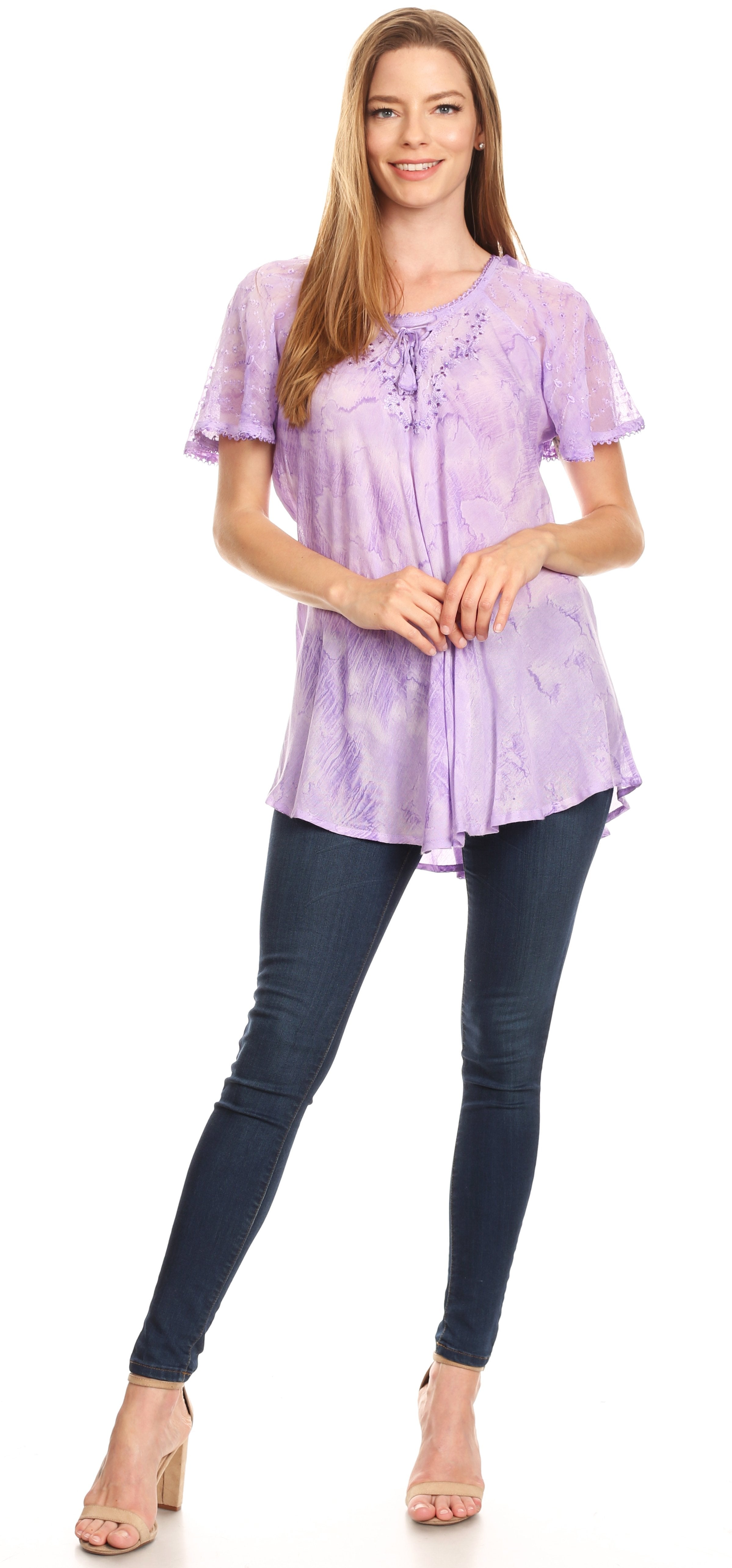 Woman wearing a light purple blouse with lace details and dark blue jeans on a white background