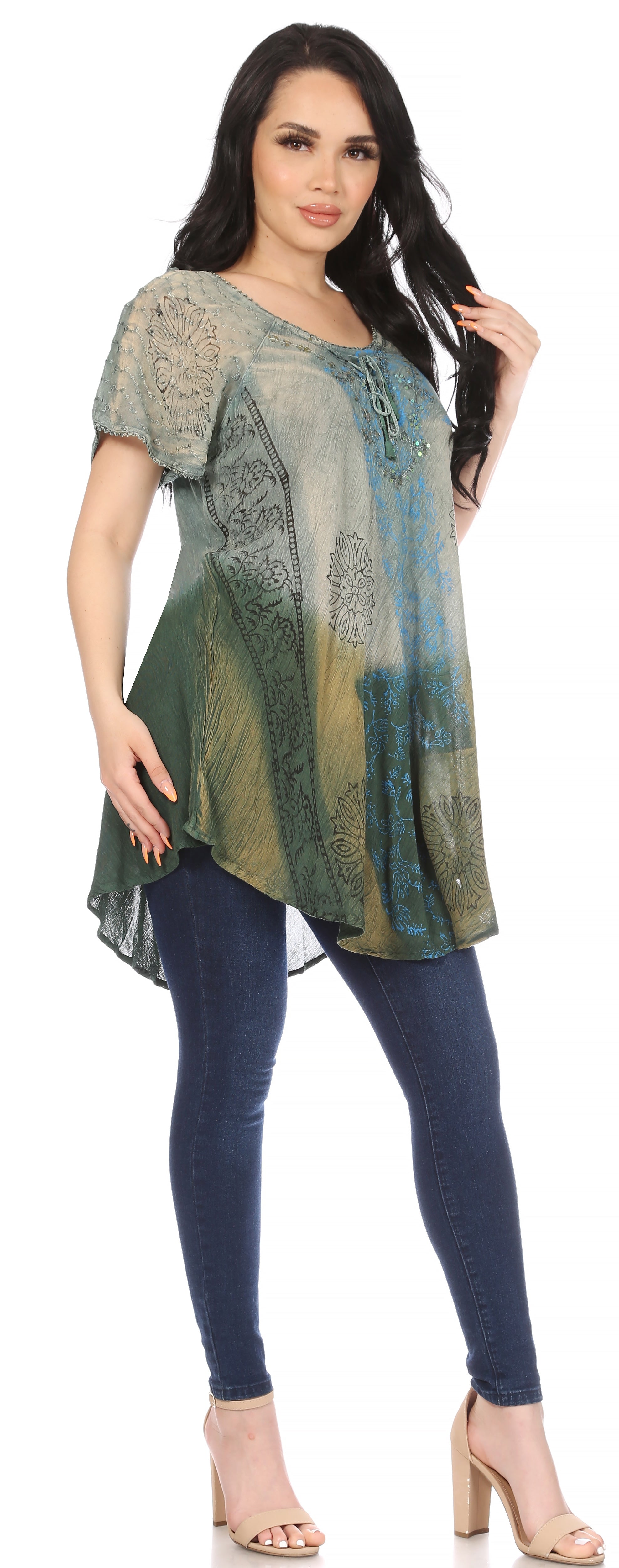 Woman wearing a patterned green and blue top with dark blue leggings on a white background