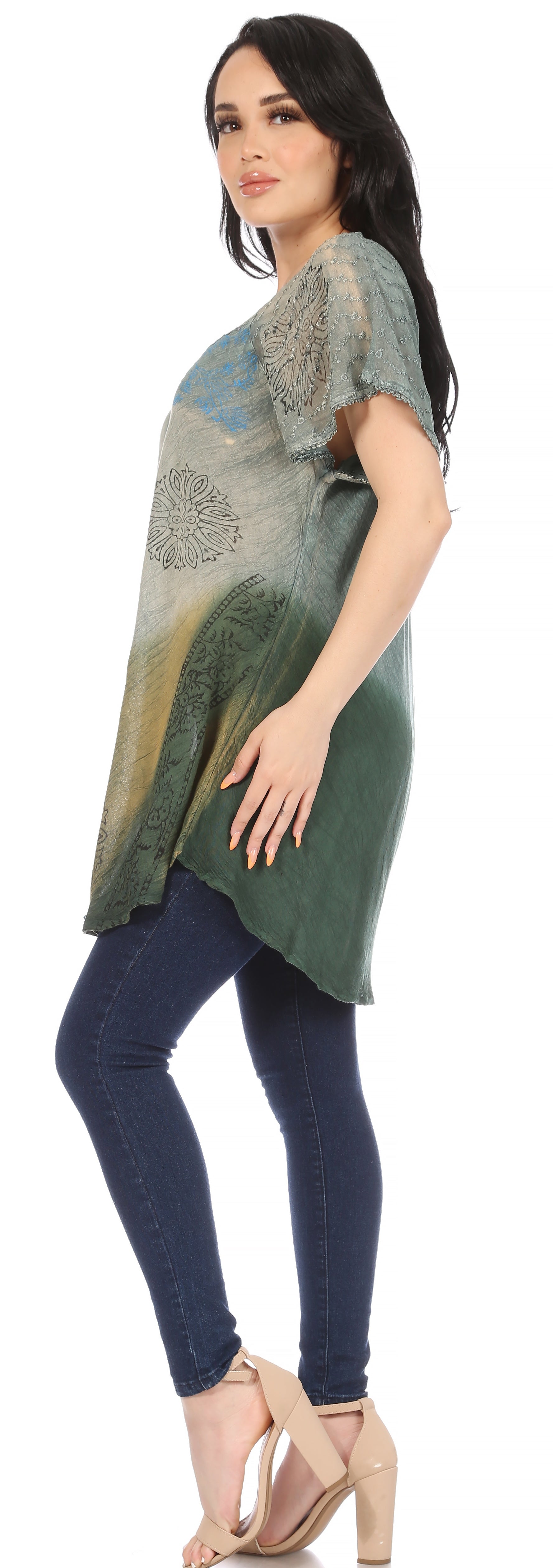 Woman wearing a green and blue patterned top with dark blue leggings on a white background
