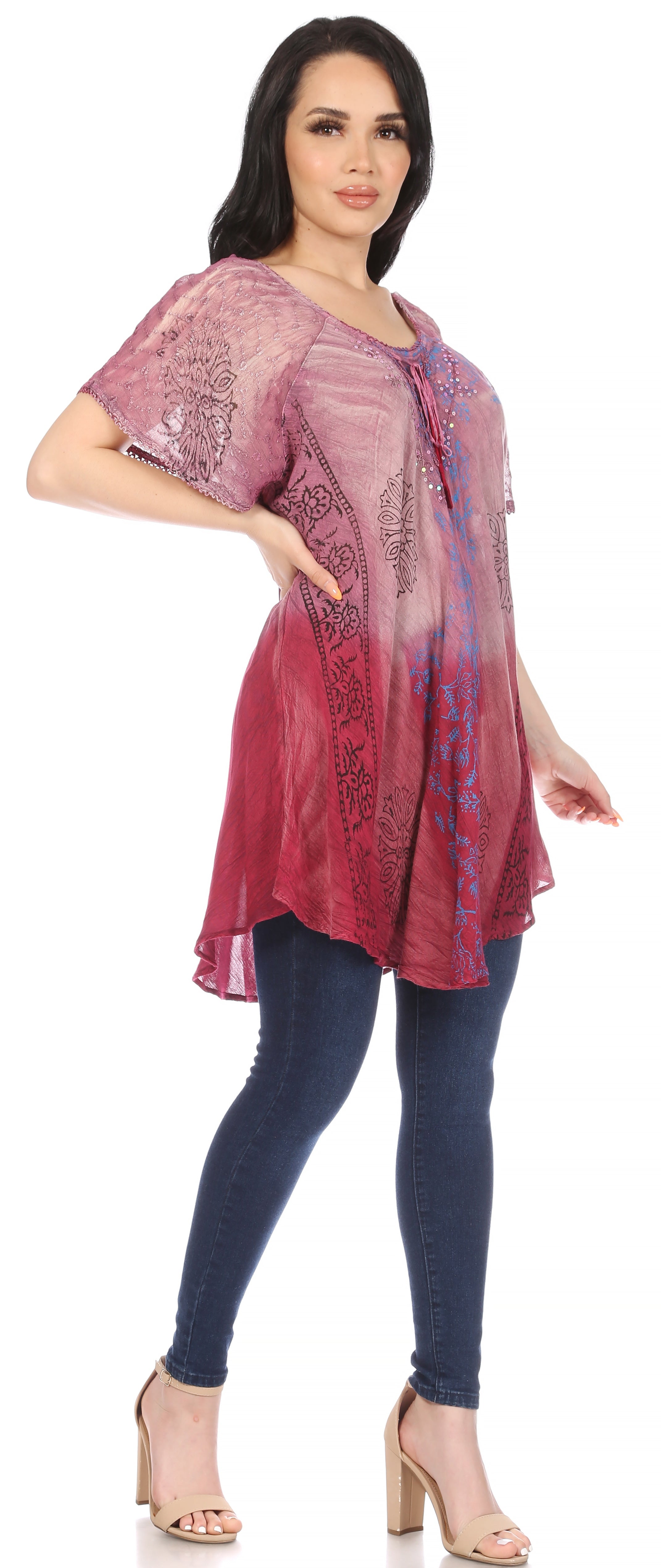 Woman wearing a pink and purple patterned top with blue leggings on a white background