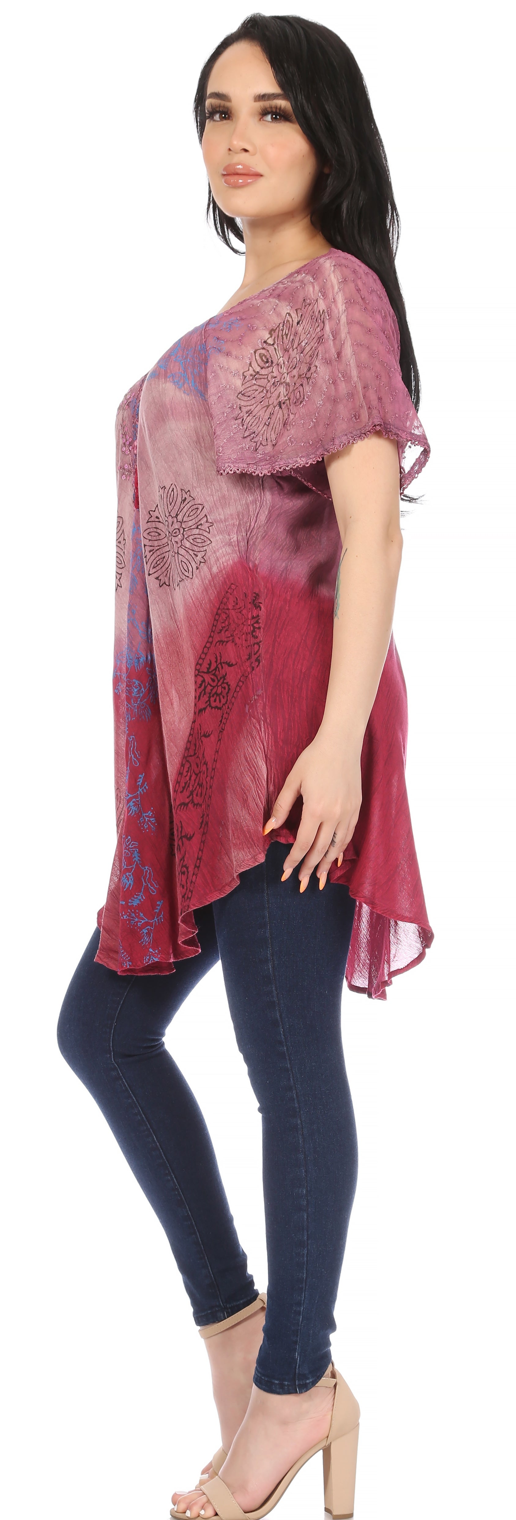 Woman wearing a pink and blue patterned top with blue jeans on a white background