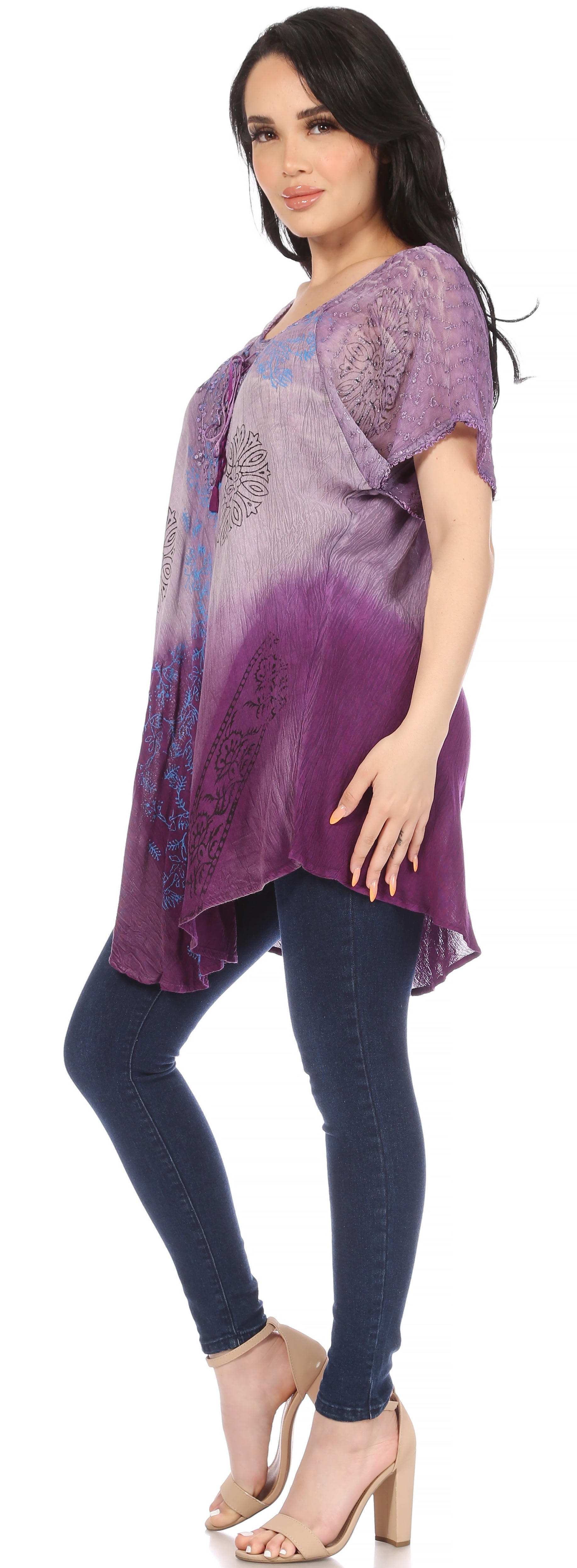 Woman wearing a purple tie-dye top and dark jeans on a white background