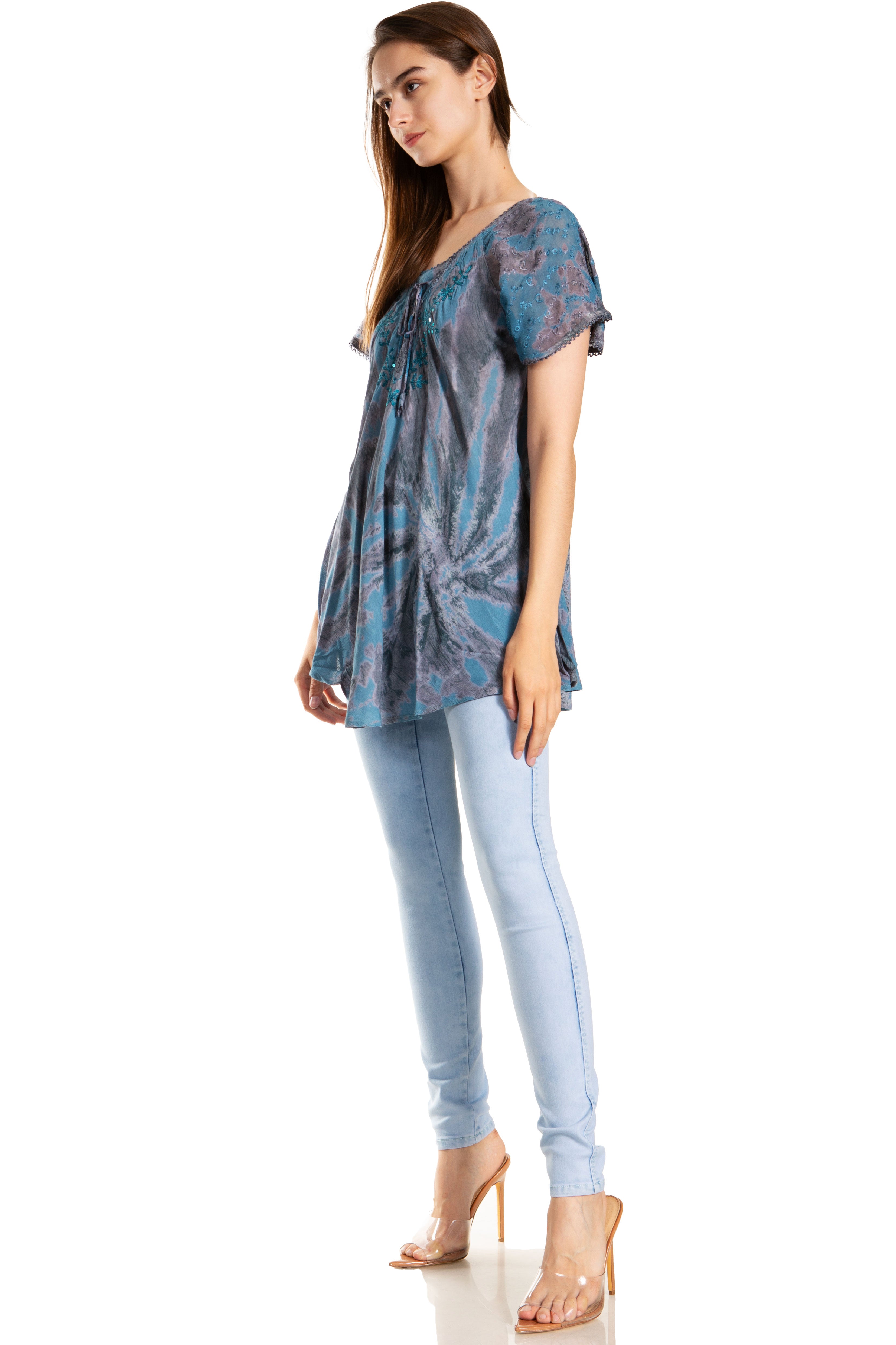 Woman wearing a blue patterned top and light blue jeans on a white background