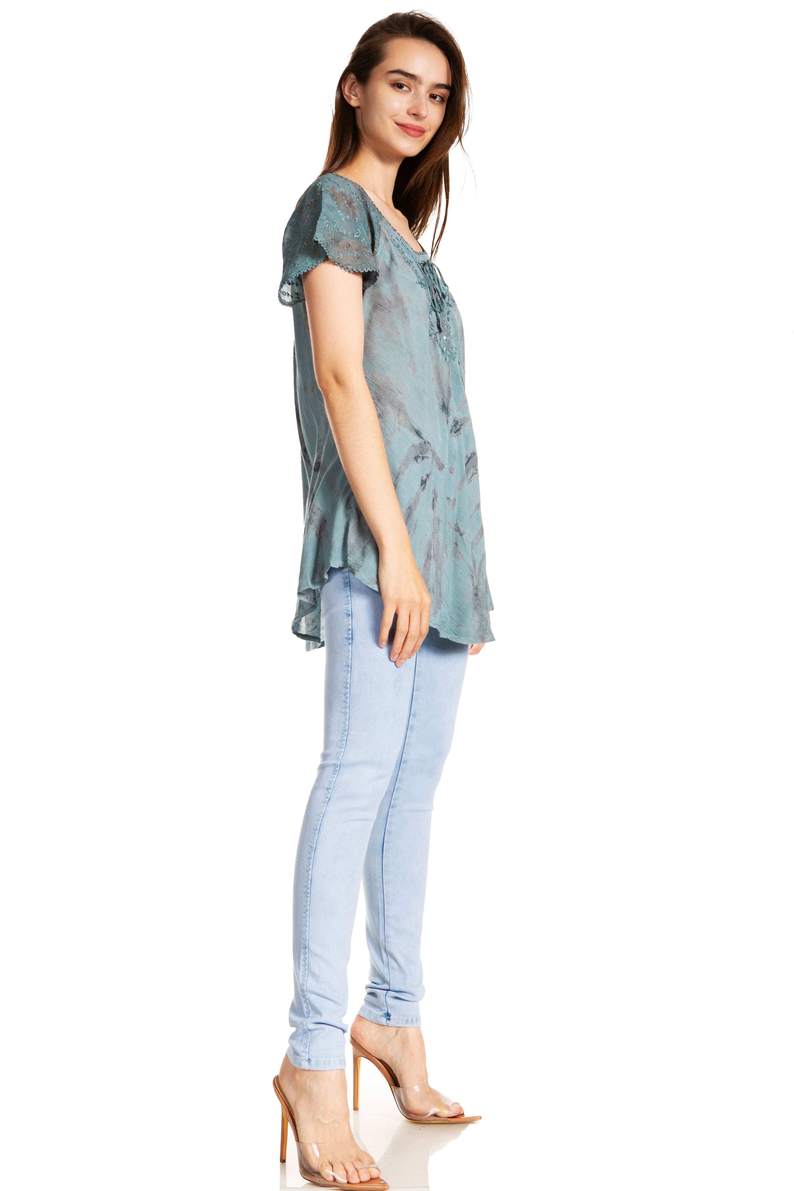 Woman wearing a patterned top and light blue jeans on a white background