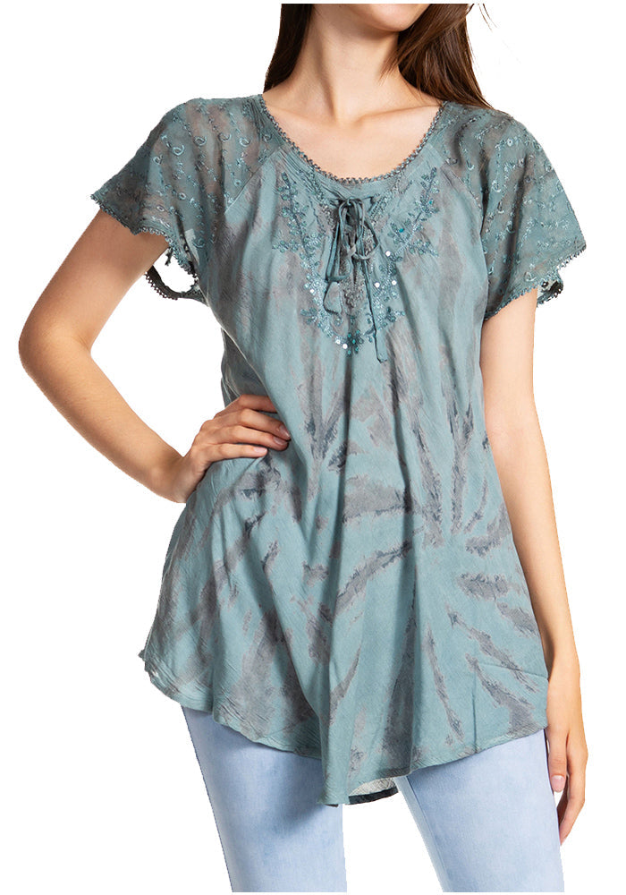 Woman wearing a teal patterned blouse with short sleeves on a white background