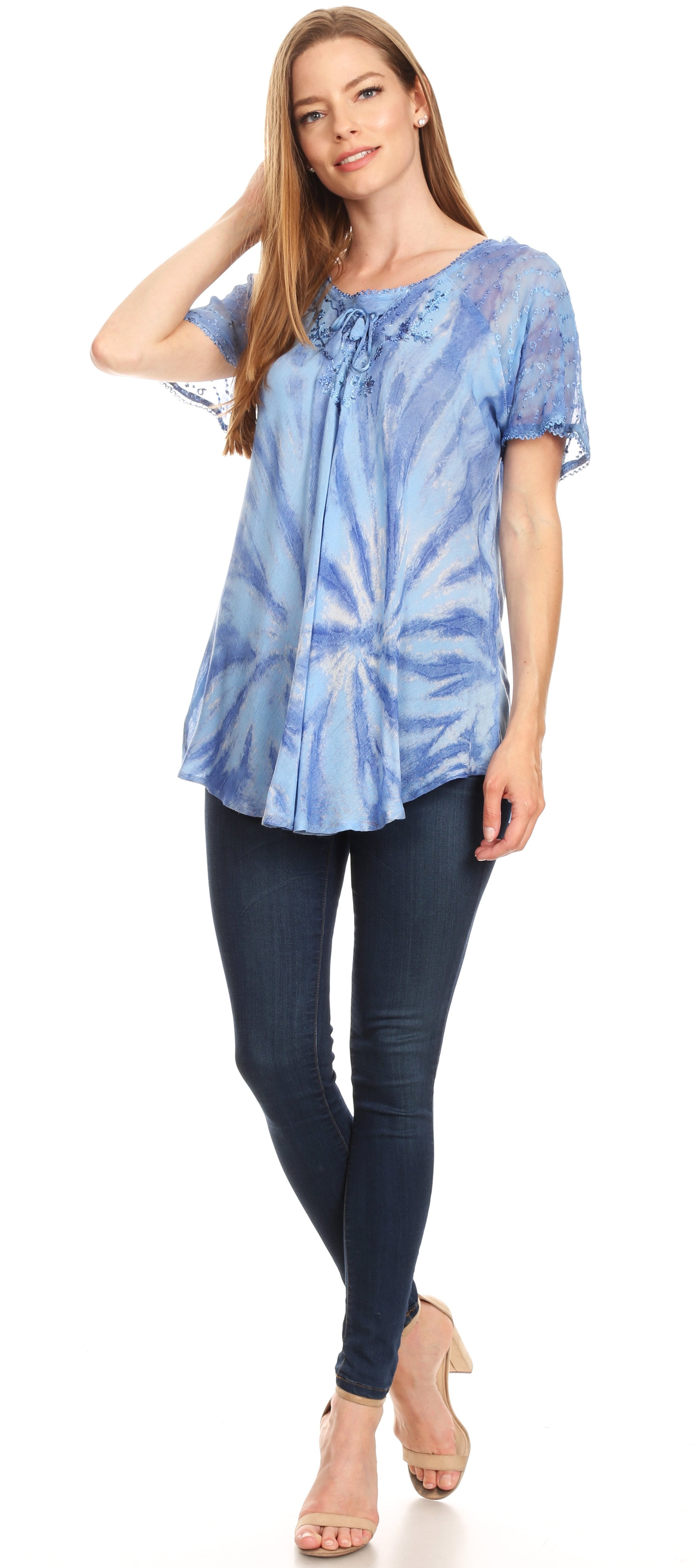 Woman wearing a blue tie-dye blouse and dark jeans on a white background