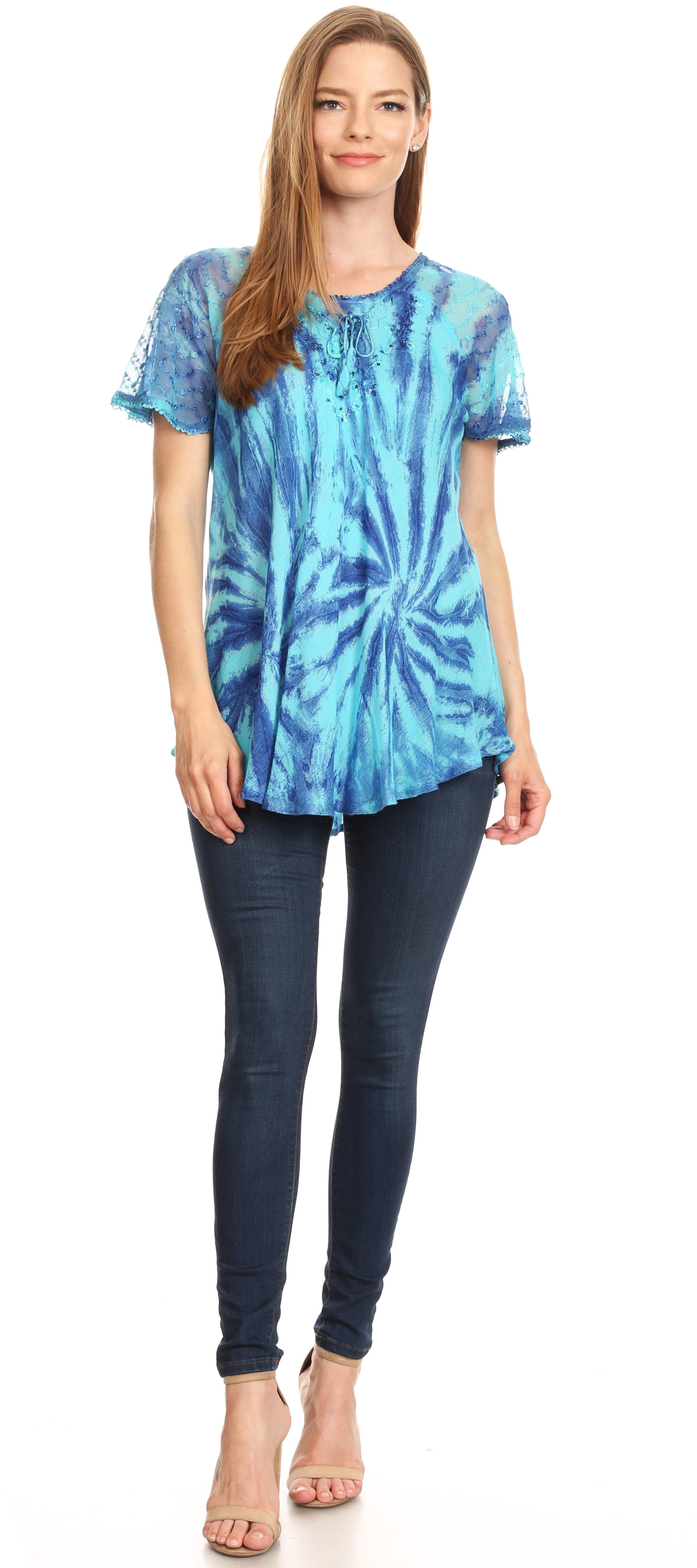 Woman wearing a blue tie-dye shirt and dark jeans on a white background