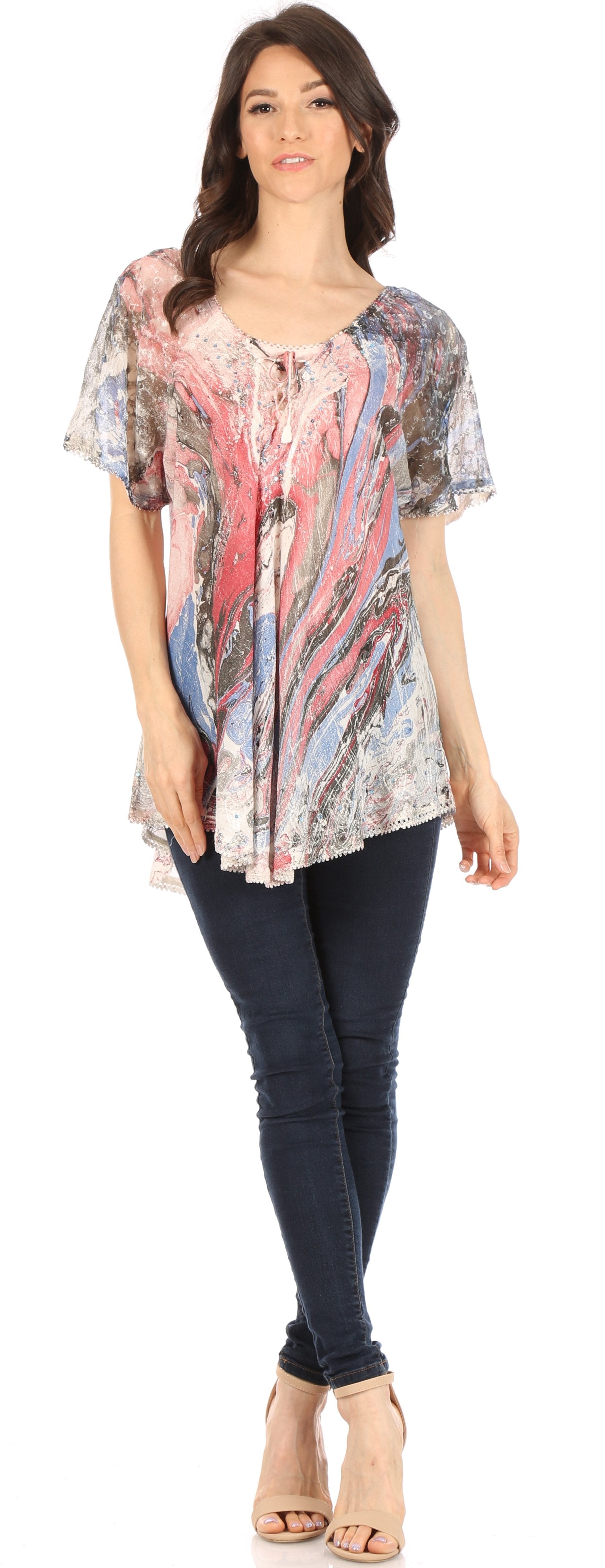 Woman wearing a patterned top and dark jeans on a white background
