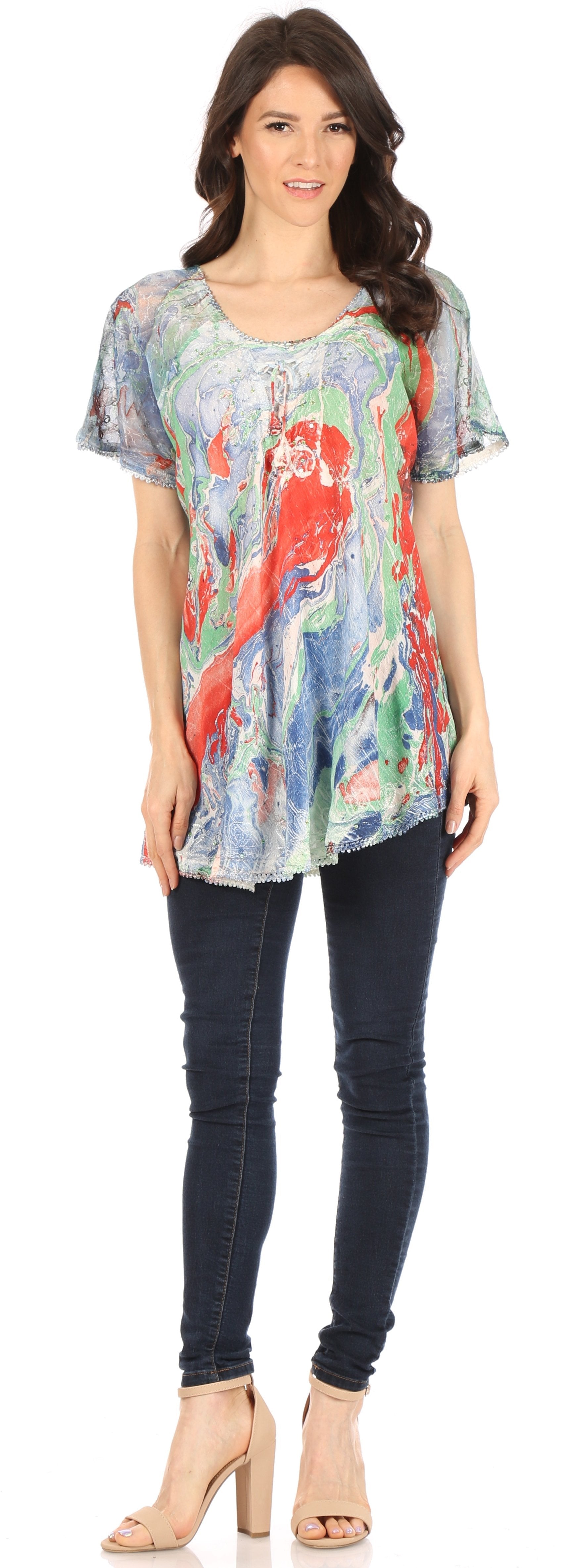 Woman wearing a colorful floral top and dark jeans on a white background