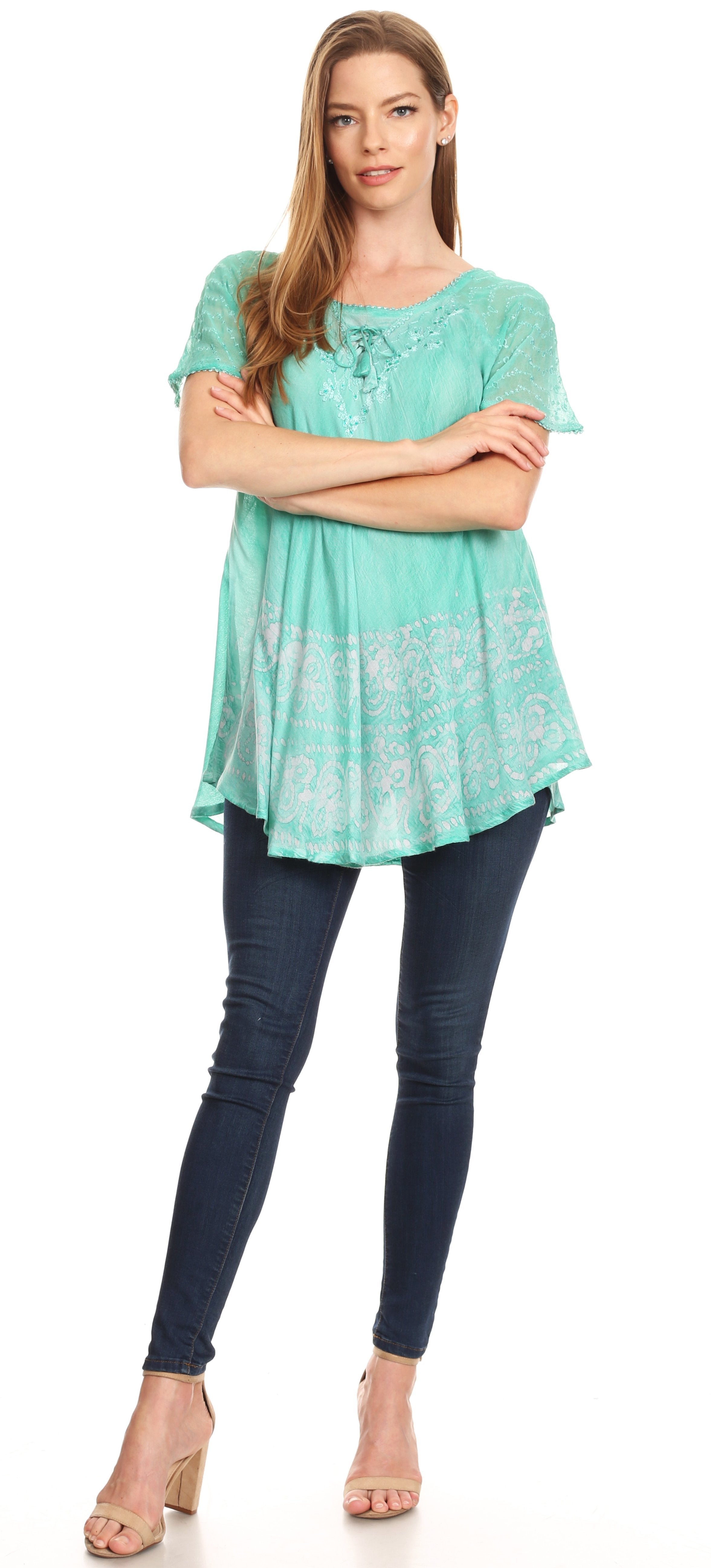Woman wearing a light blue patterned top and dark blue jeans on a white background