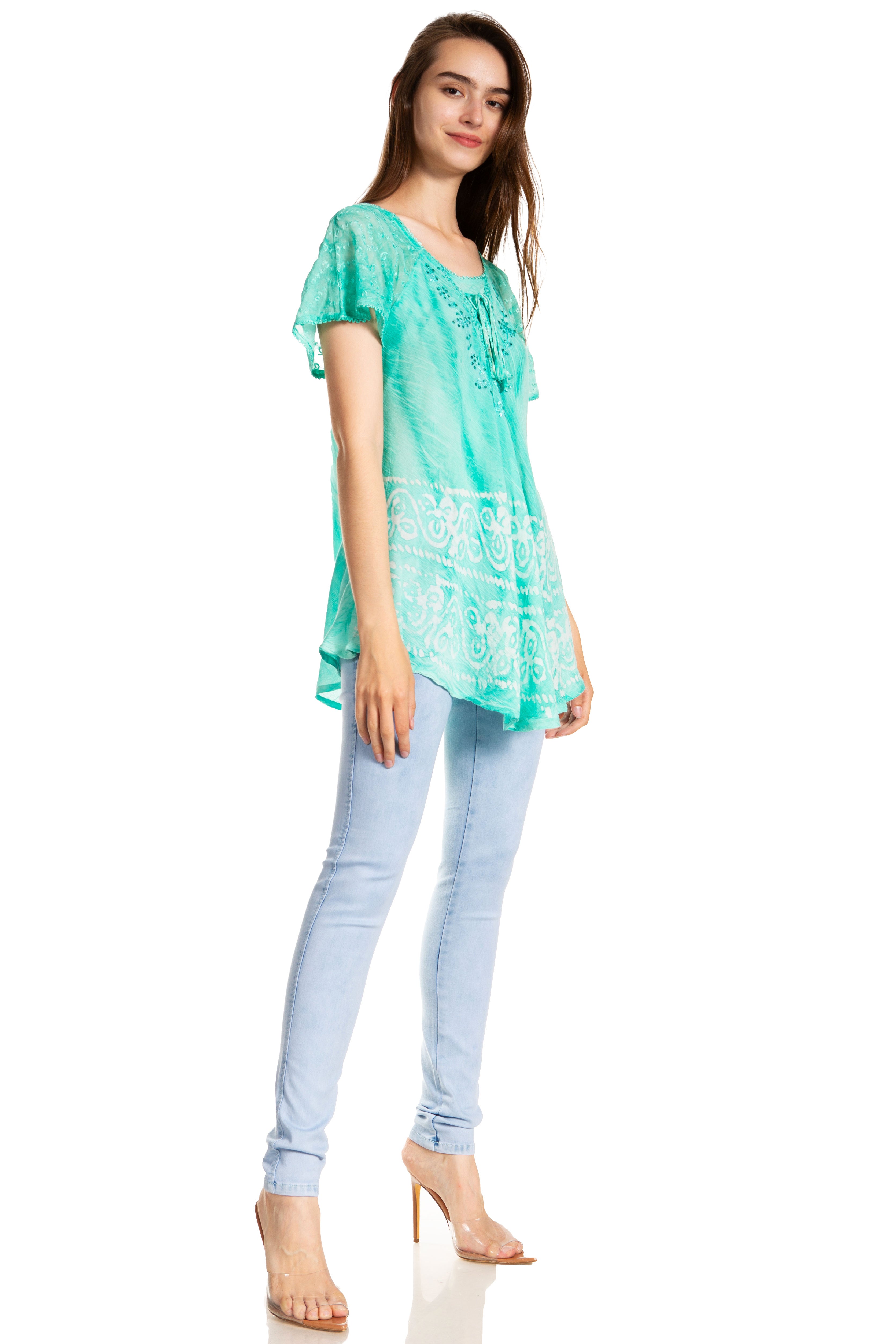 Woman wearing a turquoise lace top and light blue jeans on a white background