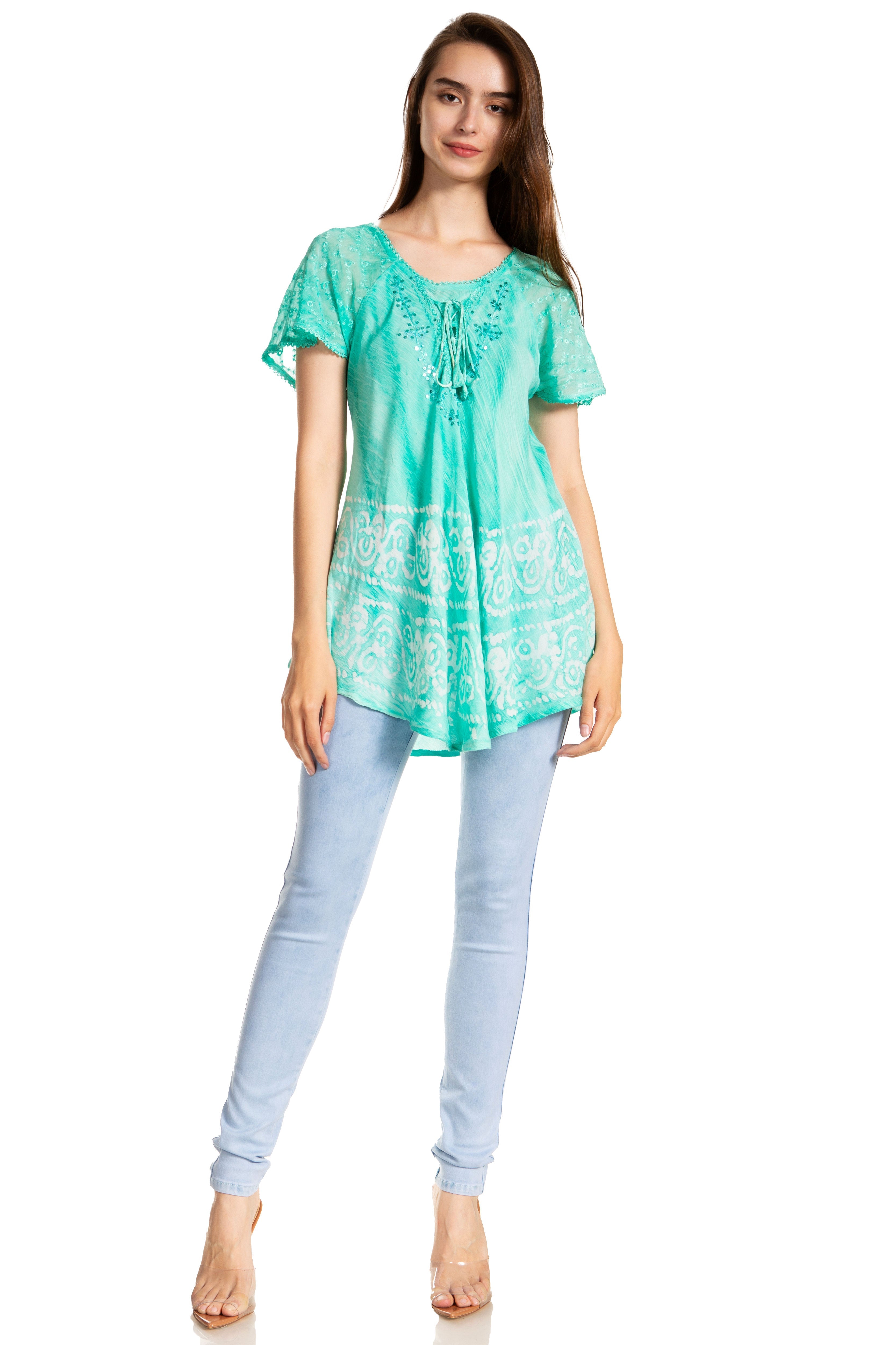 Woman wearing a green patterned top and light blue jeans on a white background