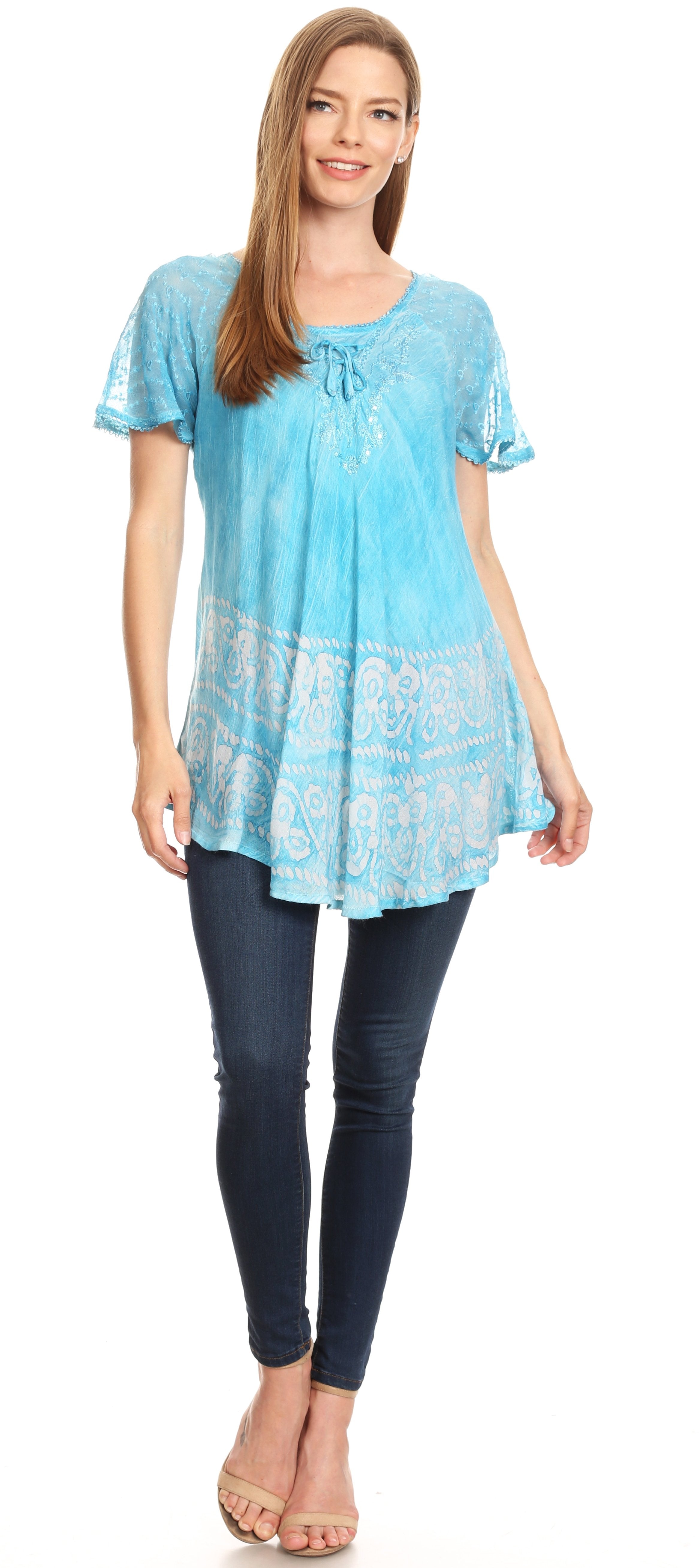 Woman wearing a light blue lace-trimmed top and dark jeans on a white background