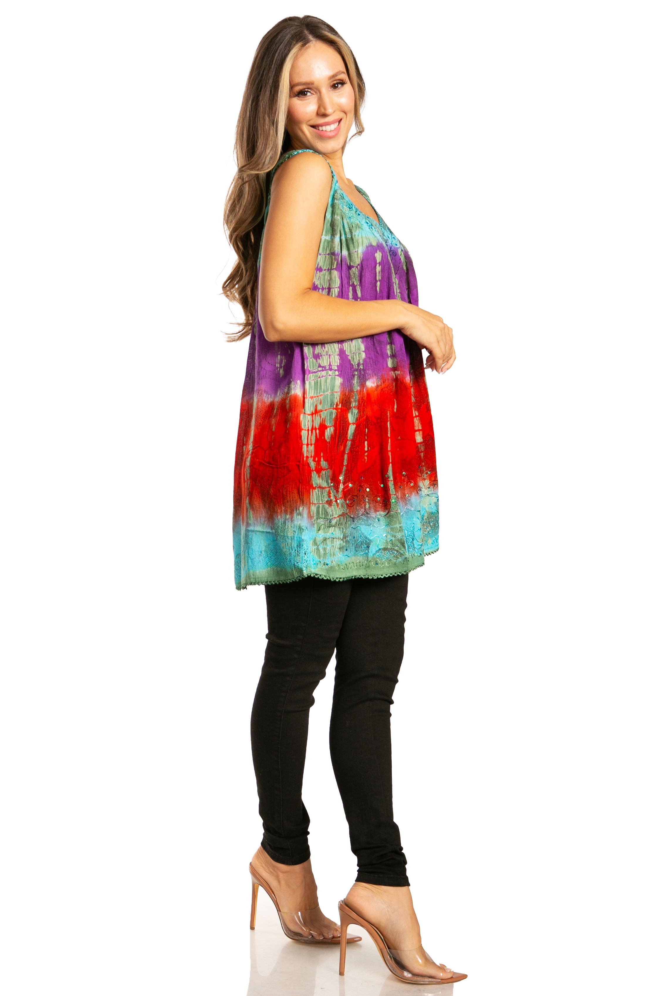 Woman wearing a colorful tie-dye top and black pants on a white background