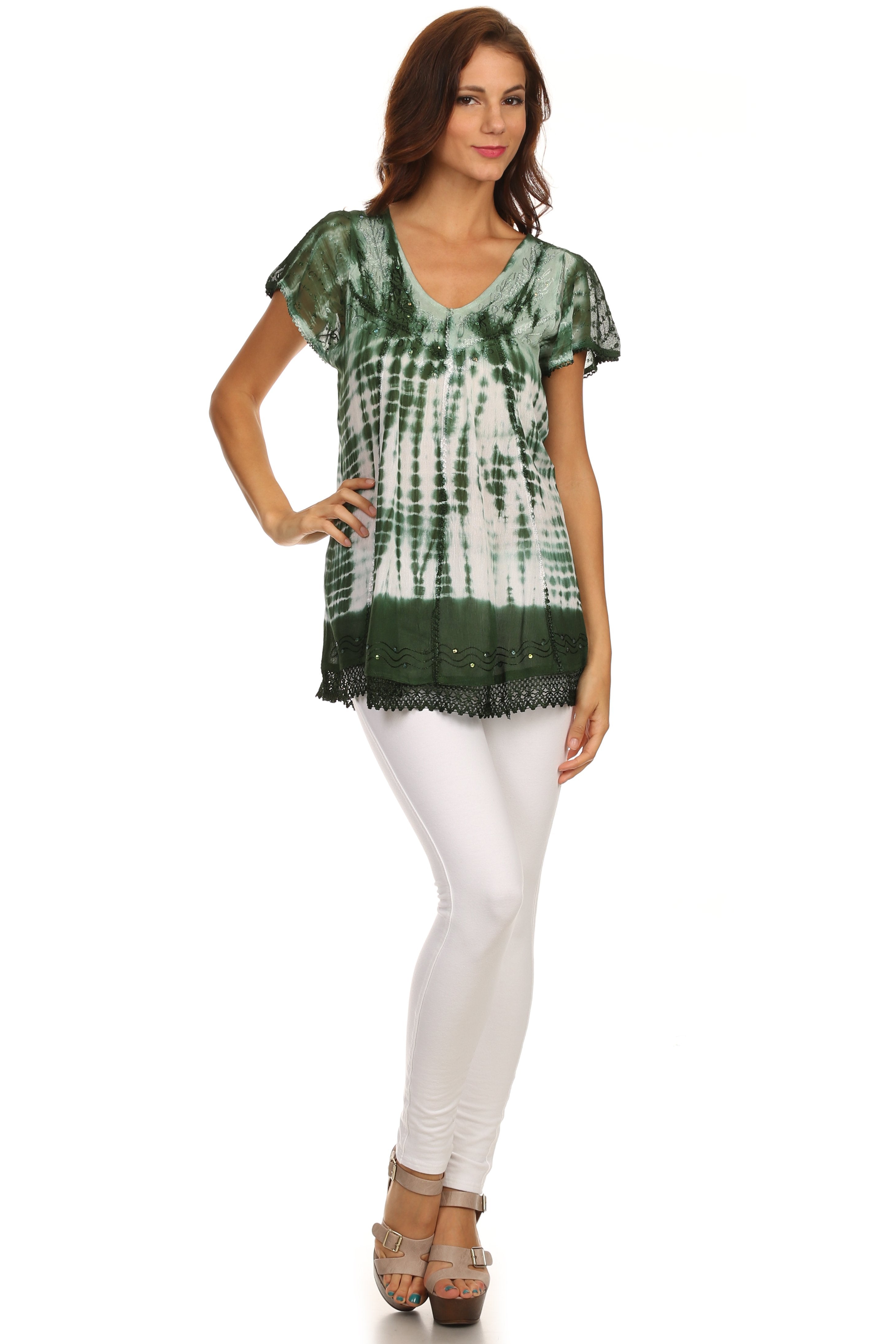 Woman wearing a green and white tie-dye top with white pants on a white background