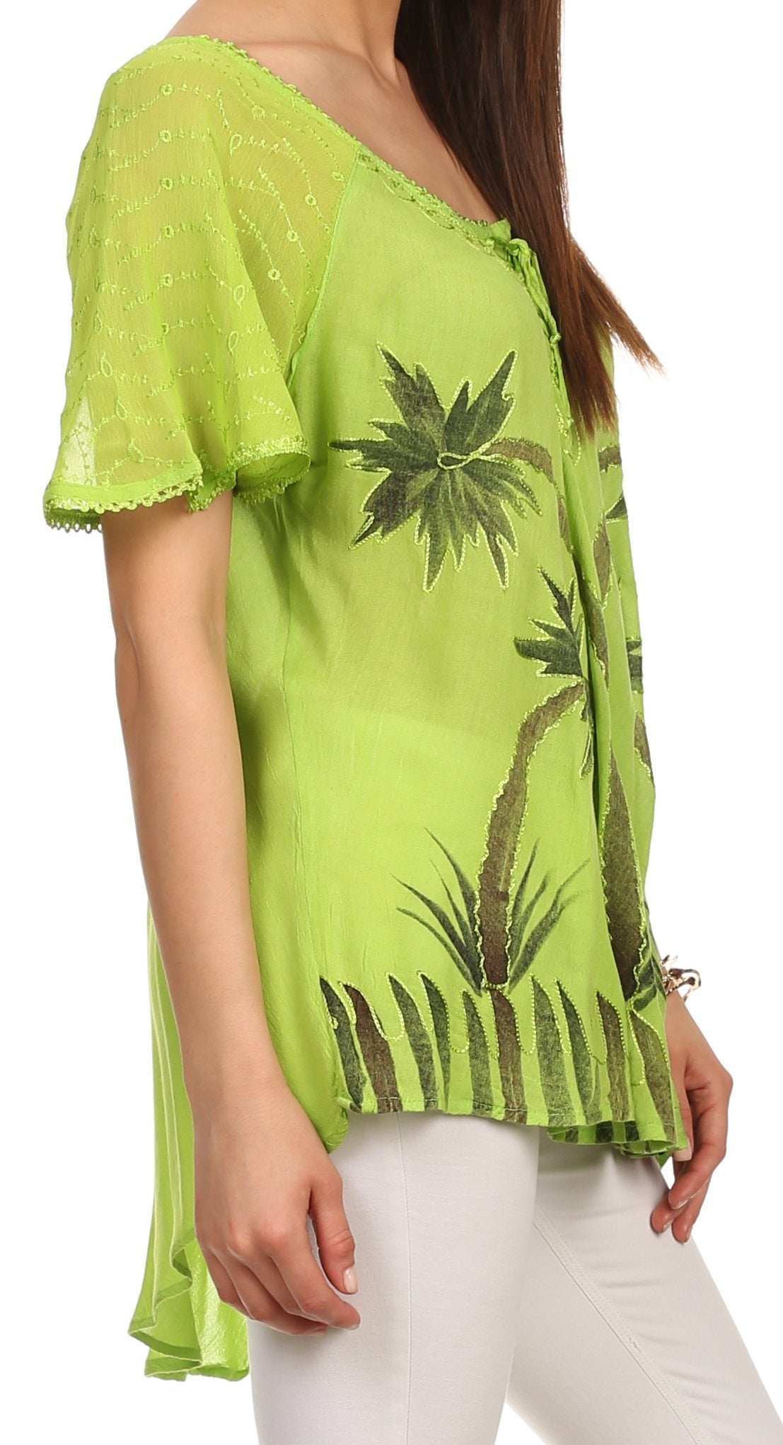 Green lace top with palm tree designs worn by a person on a white background