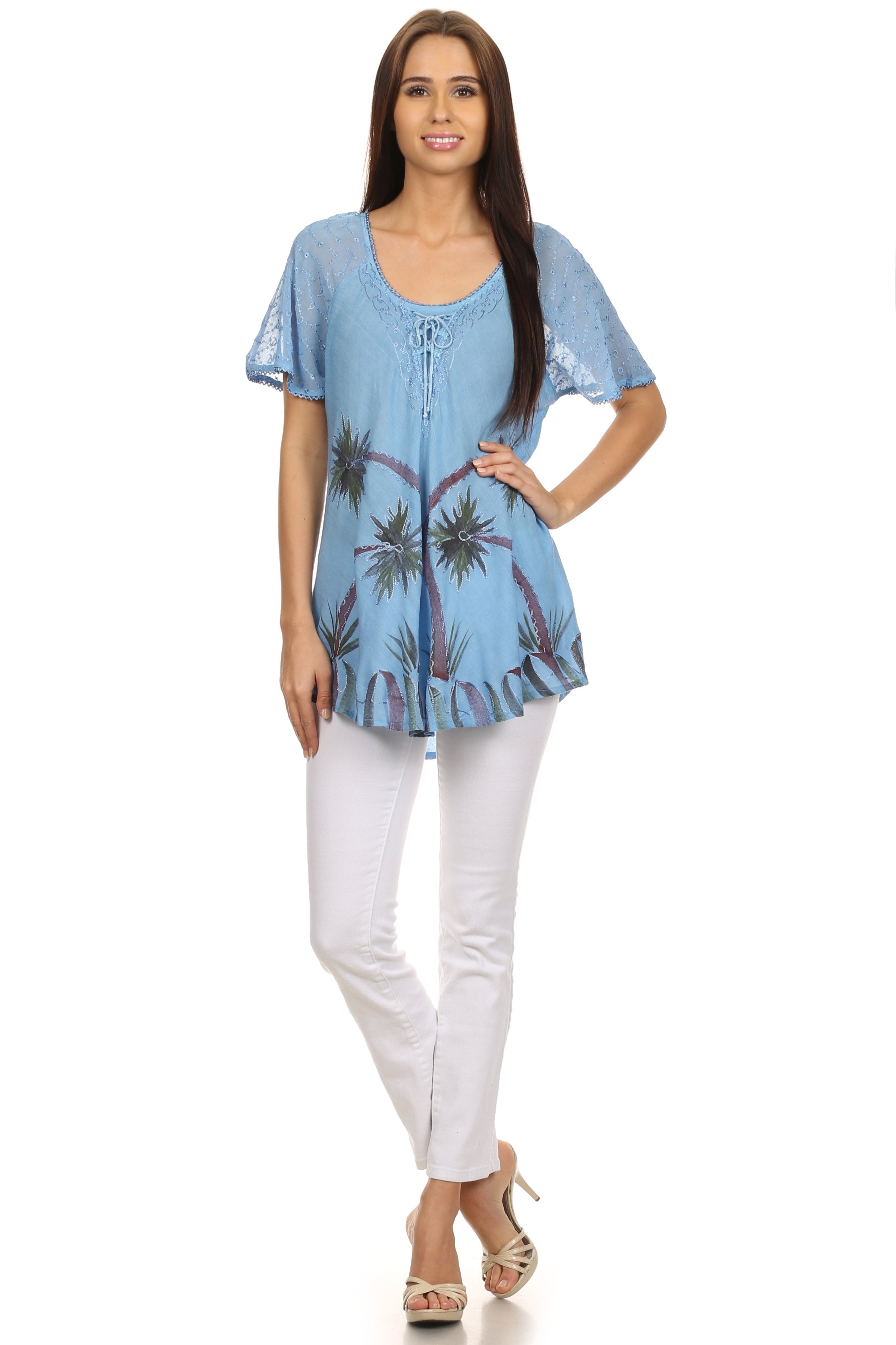 Woman wearing a light blue floral patterned top and white pants on a white background