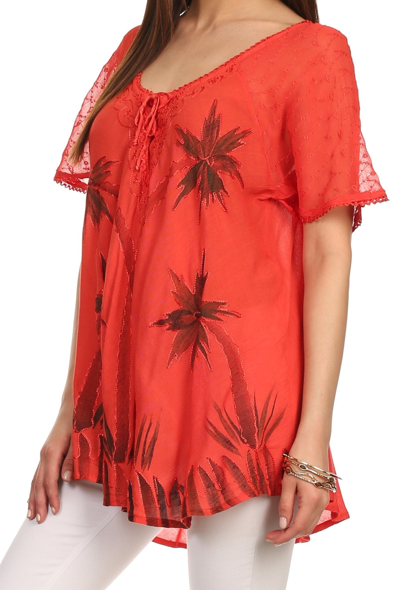 Red blouse with black floral patterns worn by a person on a white background