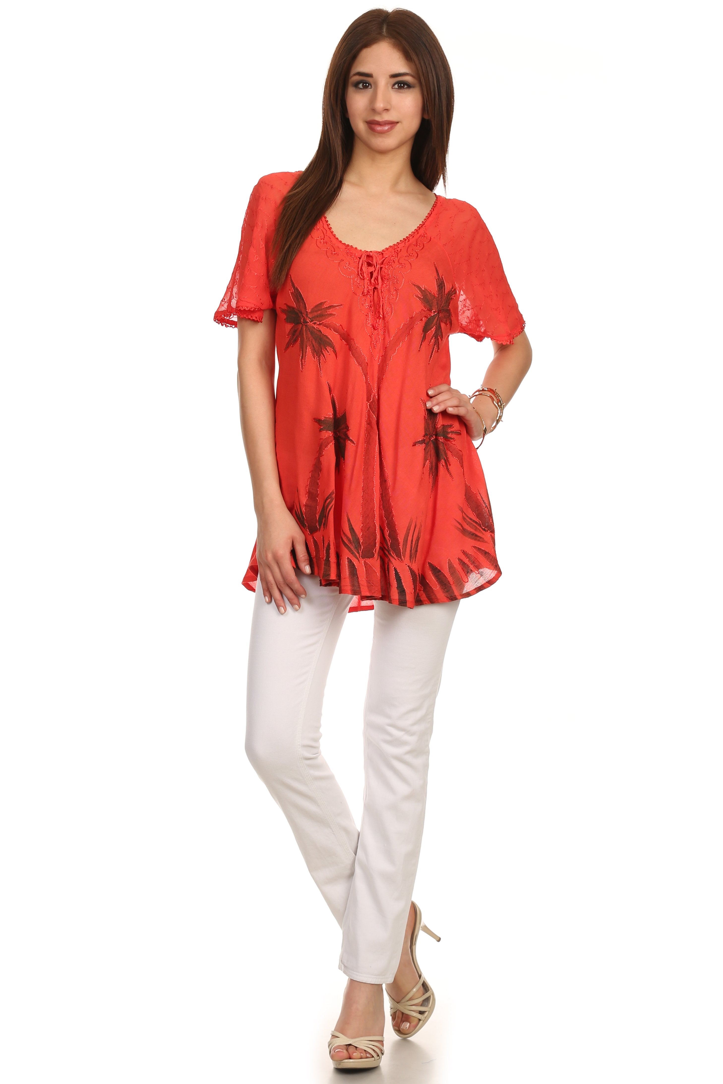 Woman wearing a red patterned top and white pants on a white background